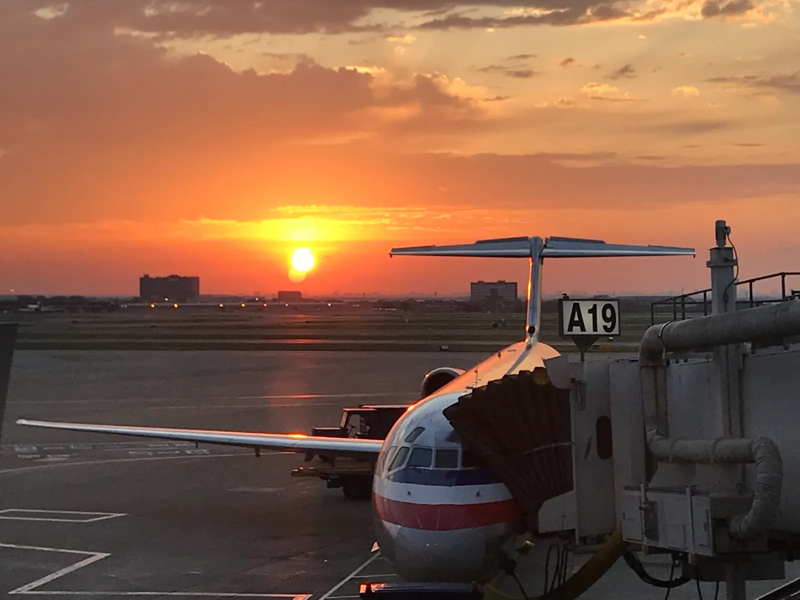 Gate A19 at DFW with an American Airlines jet parked at the jet bridge and the terminal boarding area in the foreground.