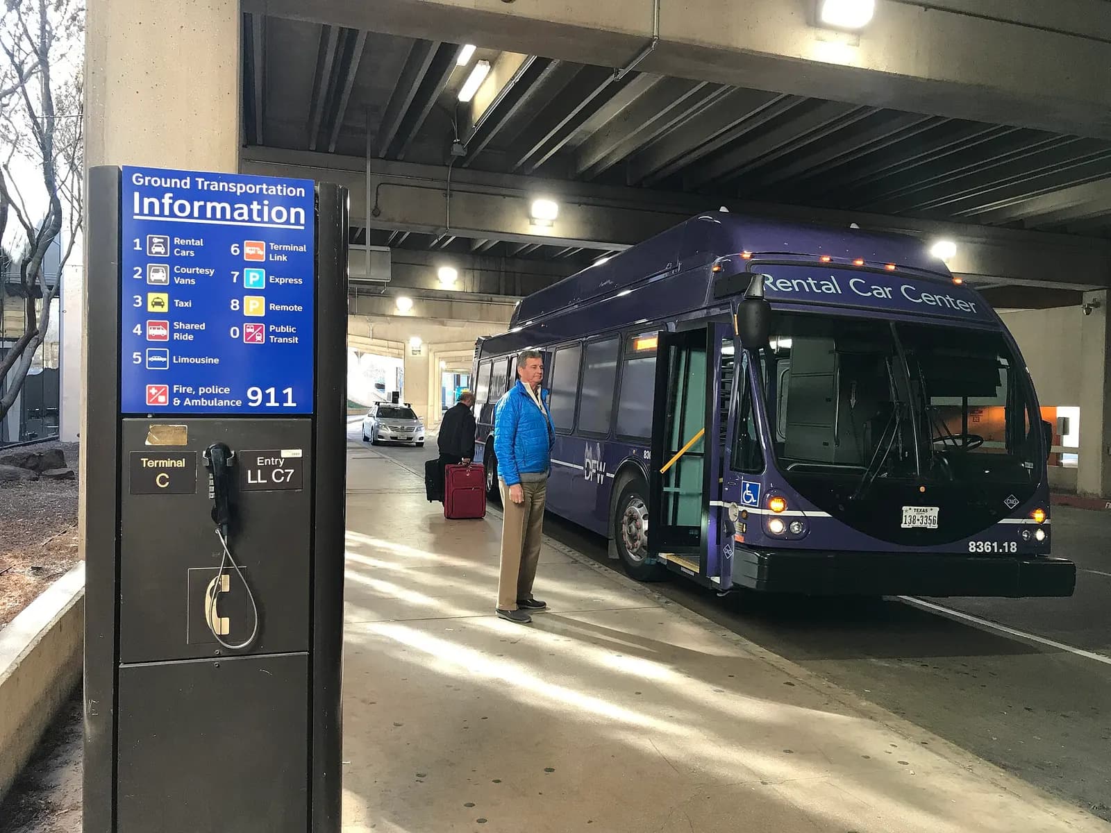A white and green rental-car shuttle bus parked outside DFW with signage directing passengers to the consolidated rental center.