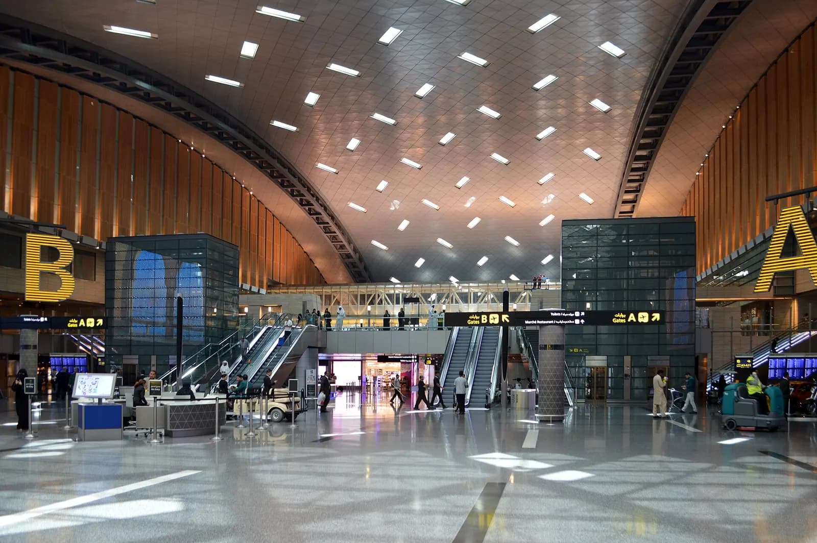 A long duty-free shopping corridor in the south concourse of Hamad International Airport lined with retail storefronts.