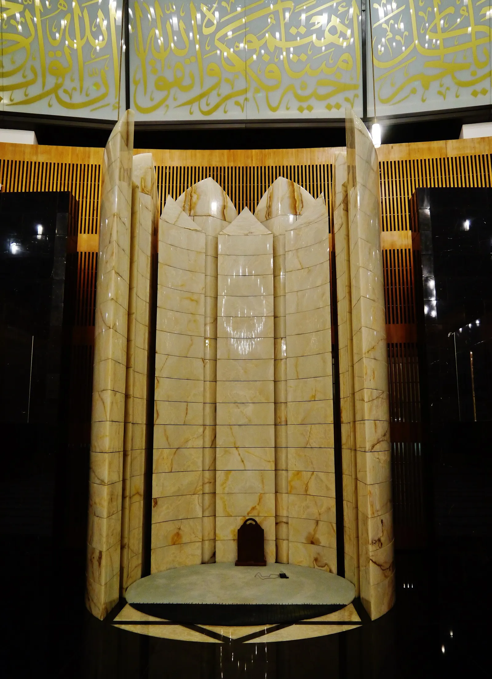 The ornate mihrab prayer niche inside the airport mosque at Hamad International Airport, lit at night.