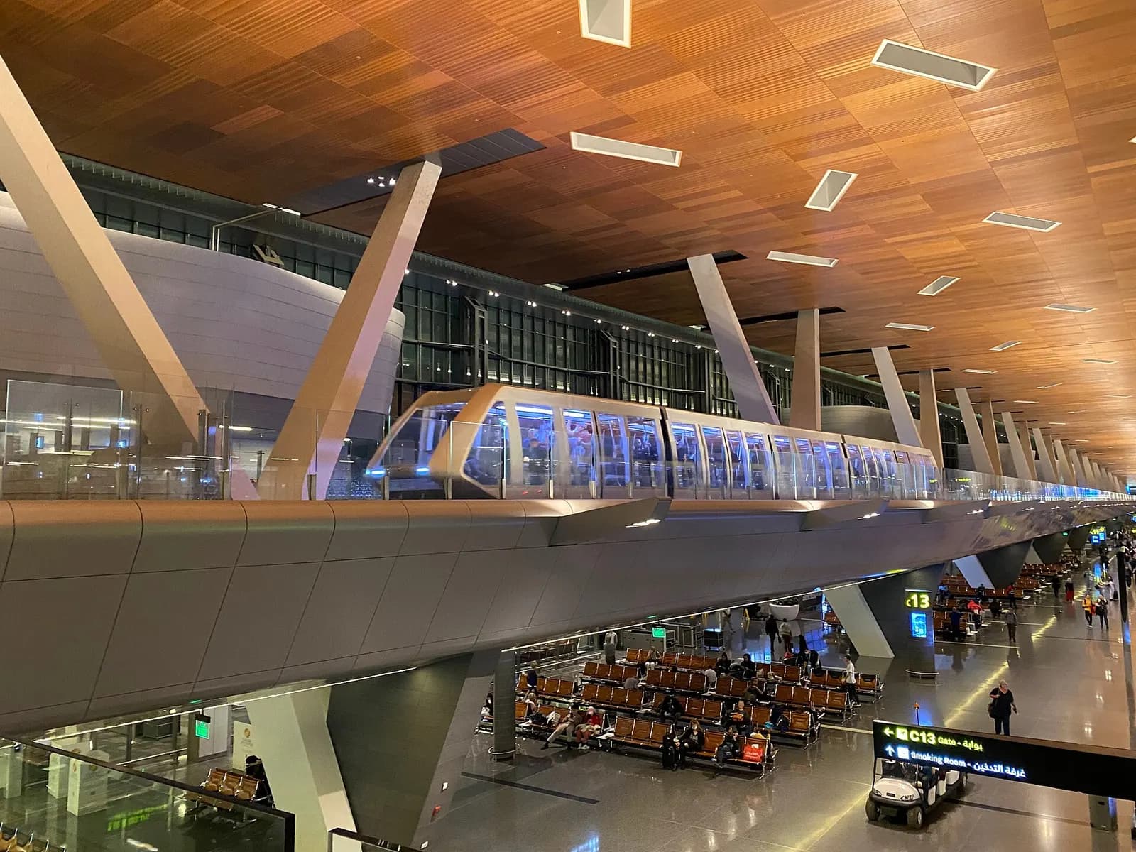 An automated people mover train on an elevated guideway inside Hamad International Airport linking terminal concourses.