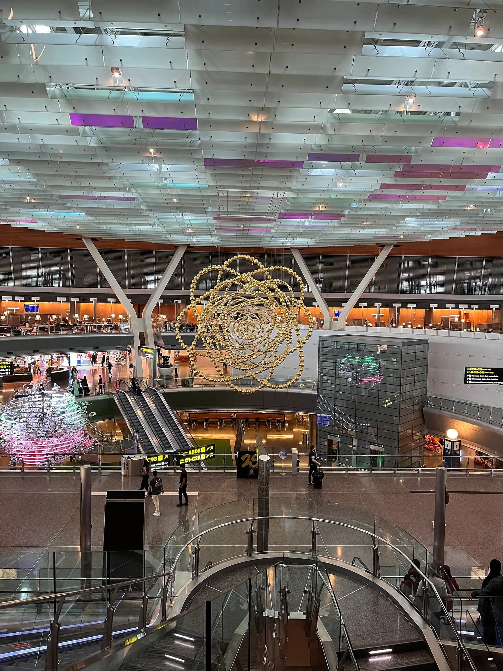 A wide, well-lit airport hall at Hamad International Airport with travelers moving through the terminal during a connection.
