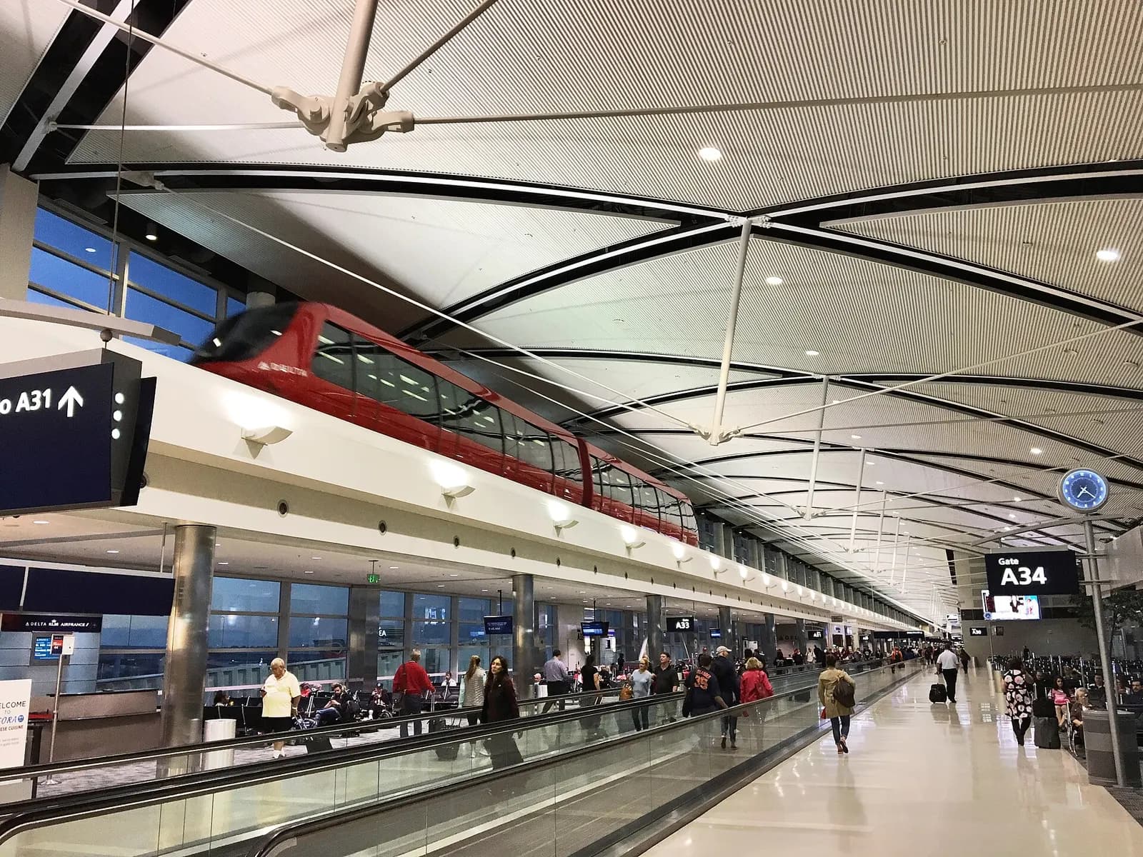 The open main hall of the McNamara Terminal with high ceilings, check-in areas, and travelers moving through the departures level.