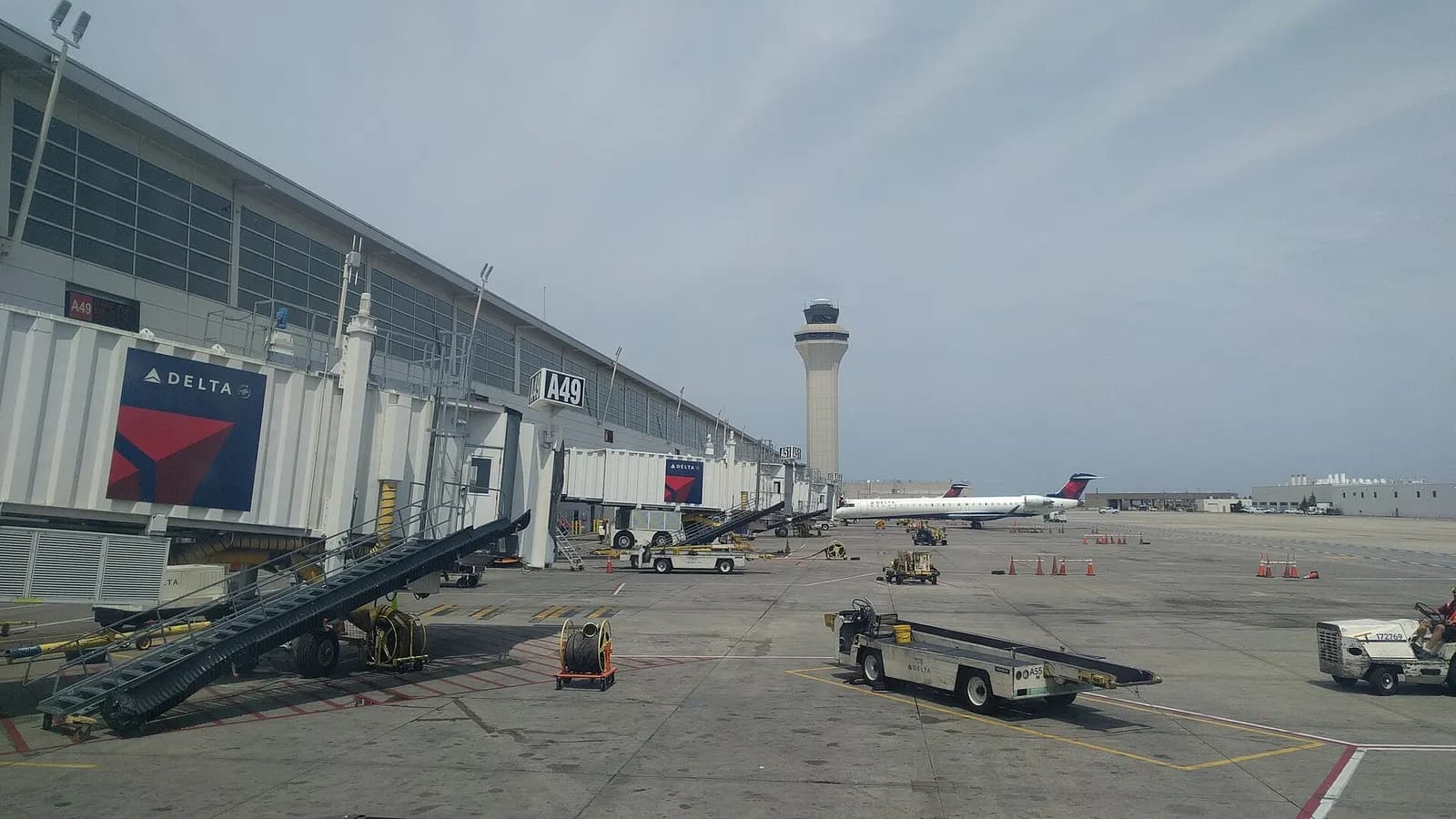 Gate-area seating and jet bridges along Concourse A with the airport control tower visible through tall terminal windows.