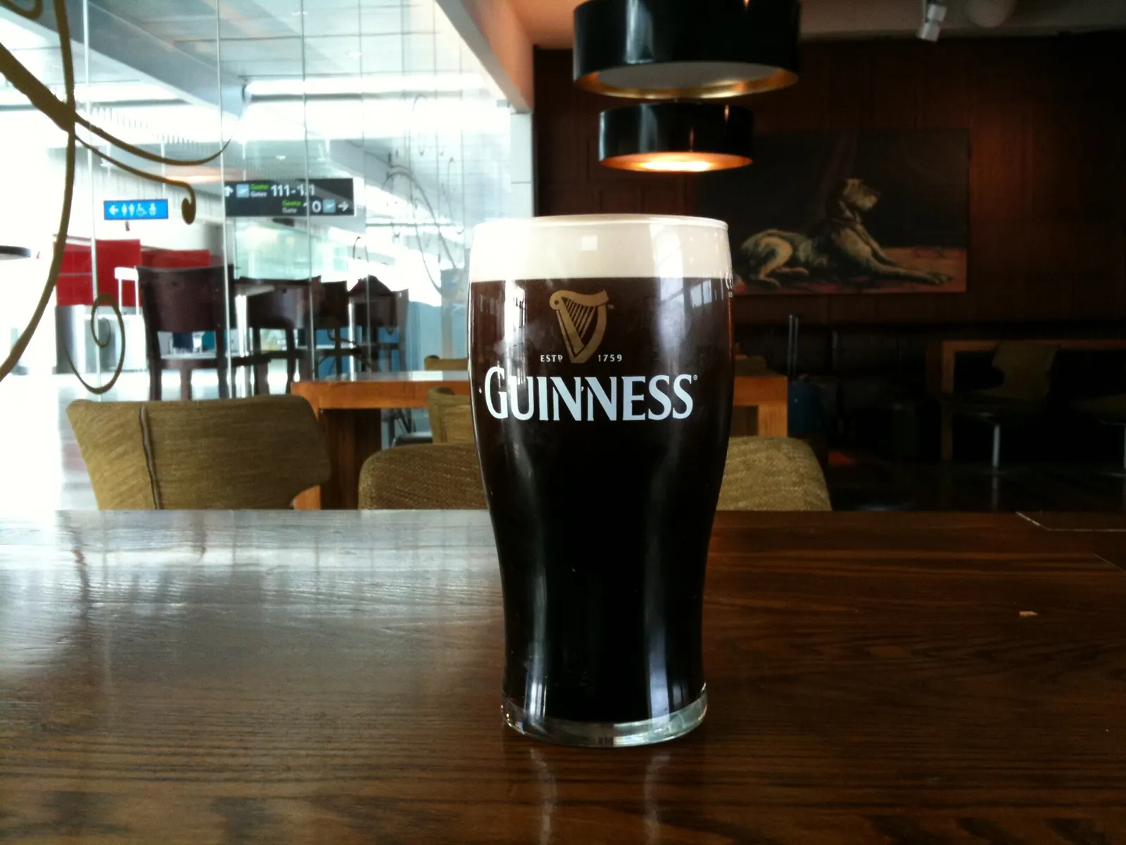 A pint of Guinness on a bar counter inside Dublin Airport, with the dark stout topped by a creamy white head.