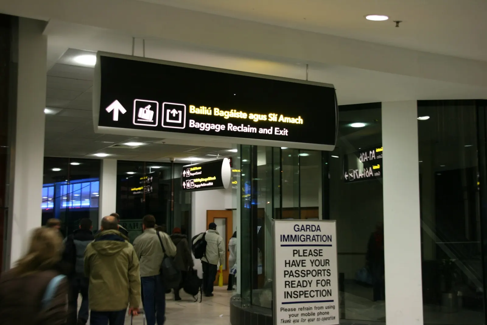 Overhead directional signs in the baggage reclaim hall showing carousel numbers in both English and Irish.
