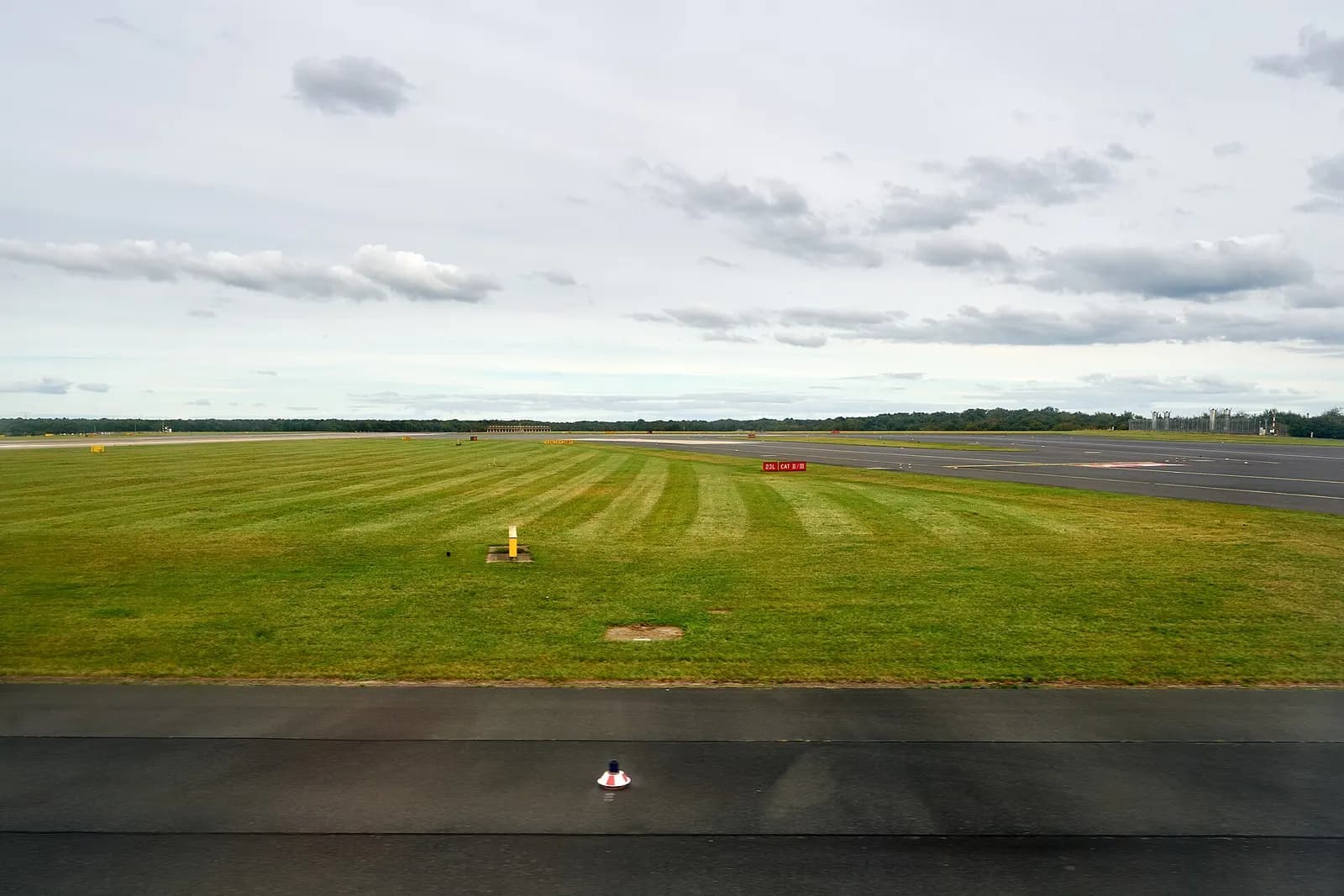 Wide view of an active runway at Düsseldorf Airport with taxiways, grass verges, and terminal buildings visible in the distance.