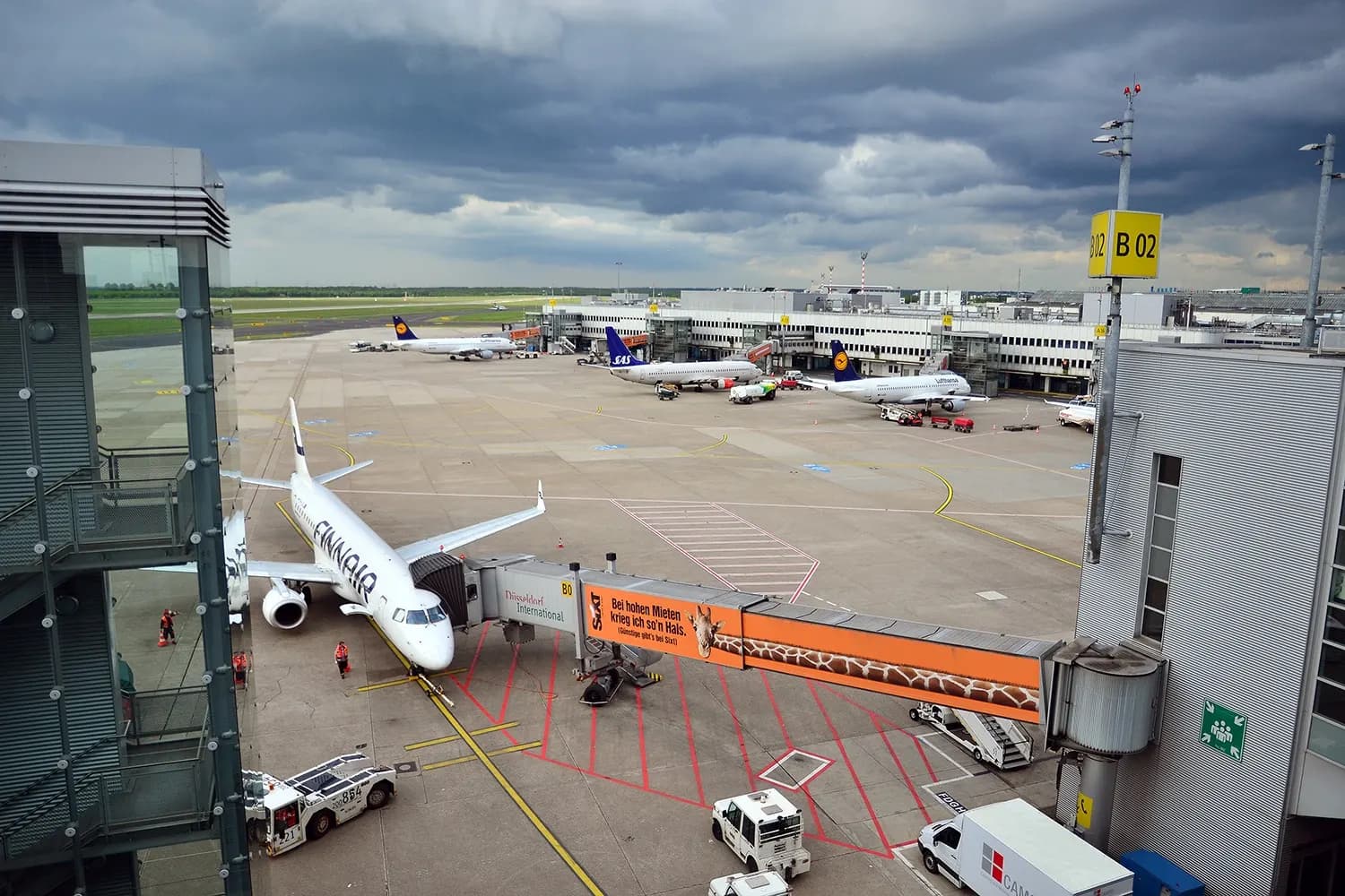 Interior of Terminal B at Düsseldorf Airport showing the departure hall with check-in areas, signage, and travelers.