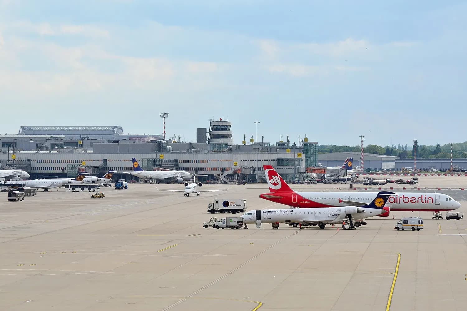 View from the Fernbahnhof platform across tracks toward the Düsseldorf Airport terminal buildings and air traffic control tower.