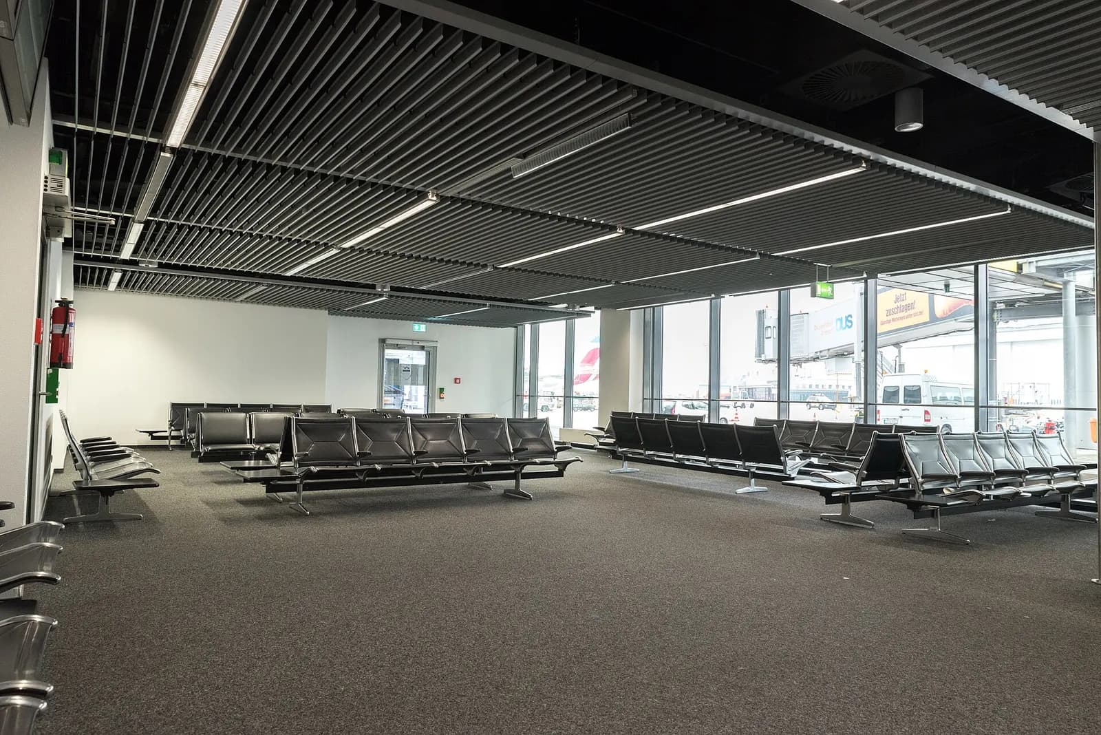 Spacious interior of Terminal A at Düsseldorf Airport with high ceilings, departure screens, shops, and passengers moving through the concourse.