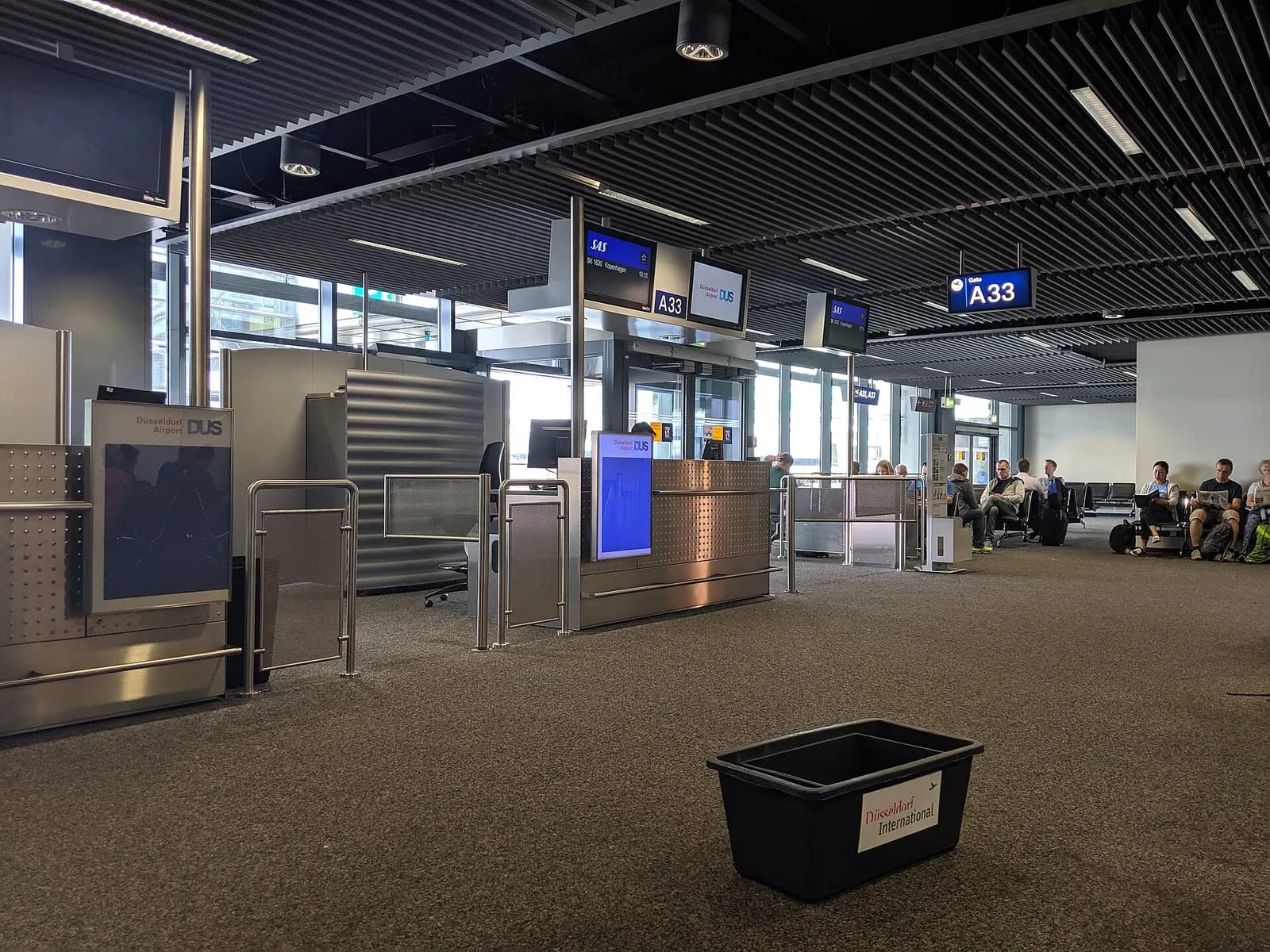 Departure gate A33 at Düsseldorf Airport with rows of seating, gate signage, and floor-to-ceiling windows overlooking the apron.