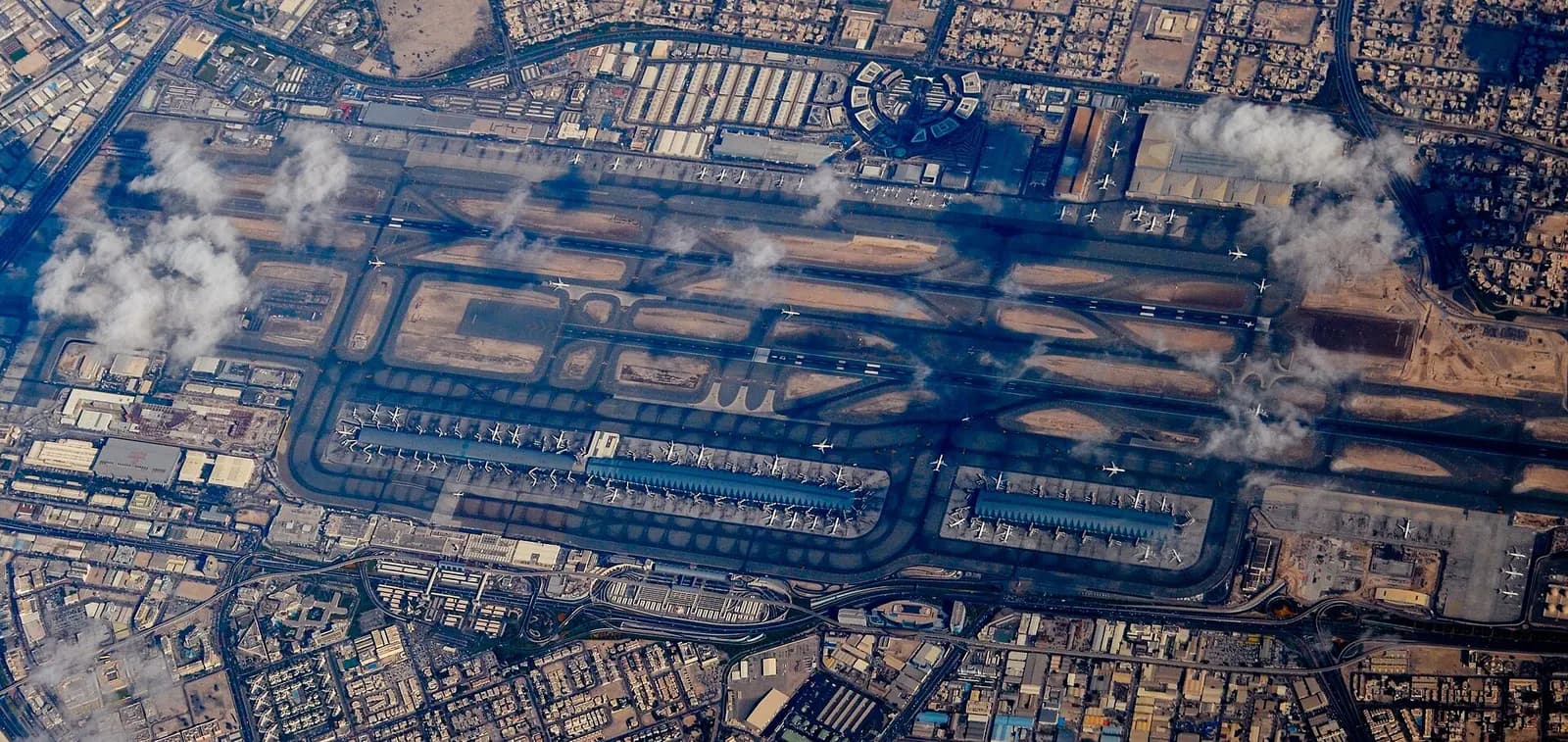 Aerial photograph of Dubai International Airport showing parallel runways, several terminal buildings, and the surrounding city and desert.