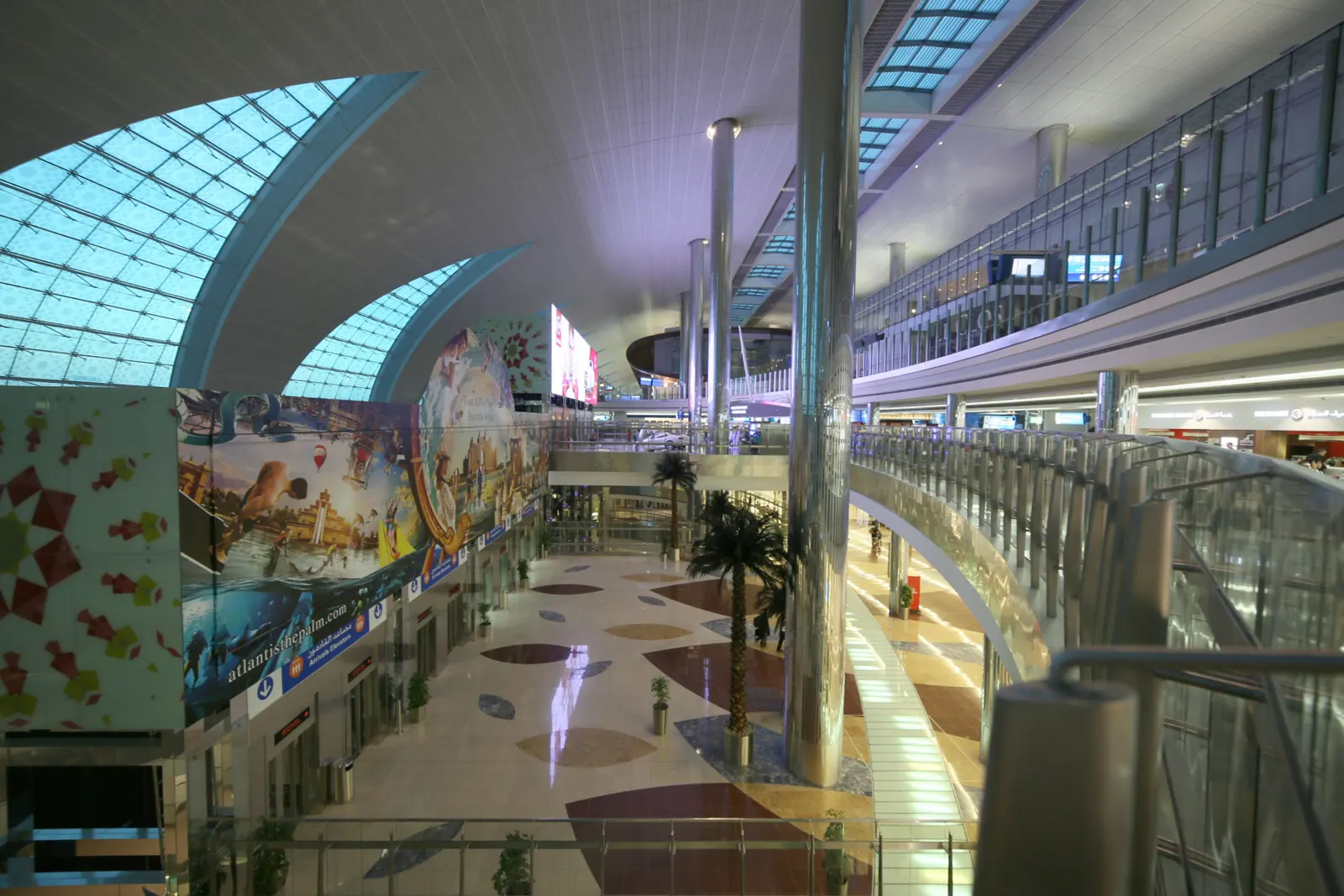 Terminal 3 at Dubai International Airport at dawn, with its long curved facade and apron lighting.