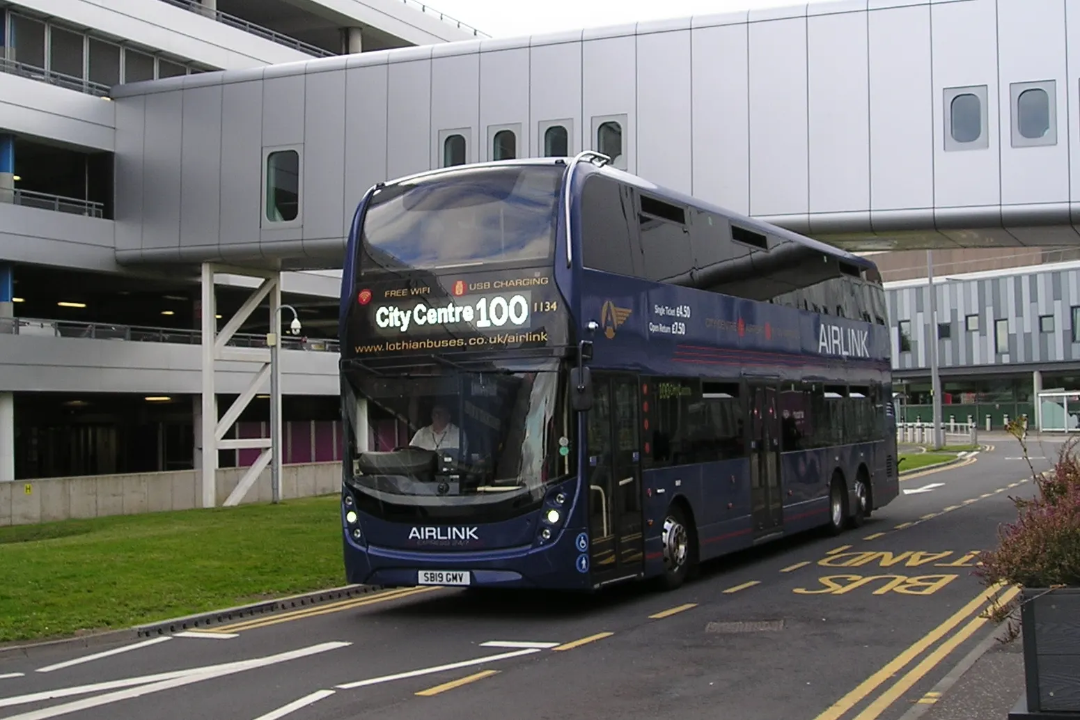 A Lothian Buses double-decker coach arriving at the Edinburgh Airport bus stops outside the terminal.