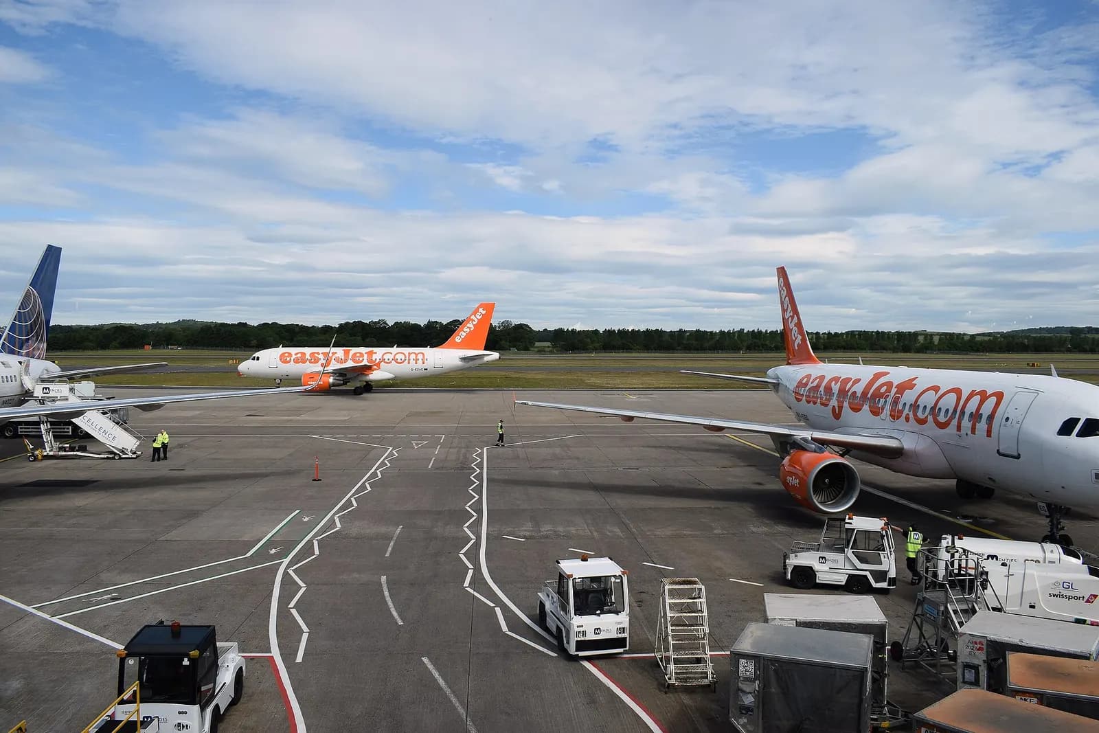 A busy apron at Edinburgh Airport with multiple airliners parked at gates and ground vehicles moving between aircraft.