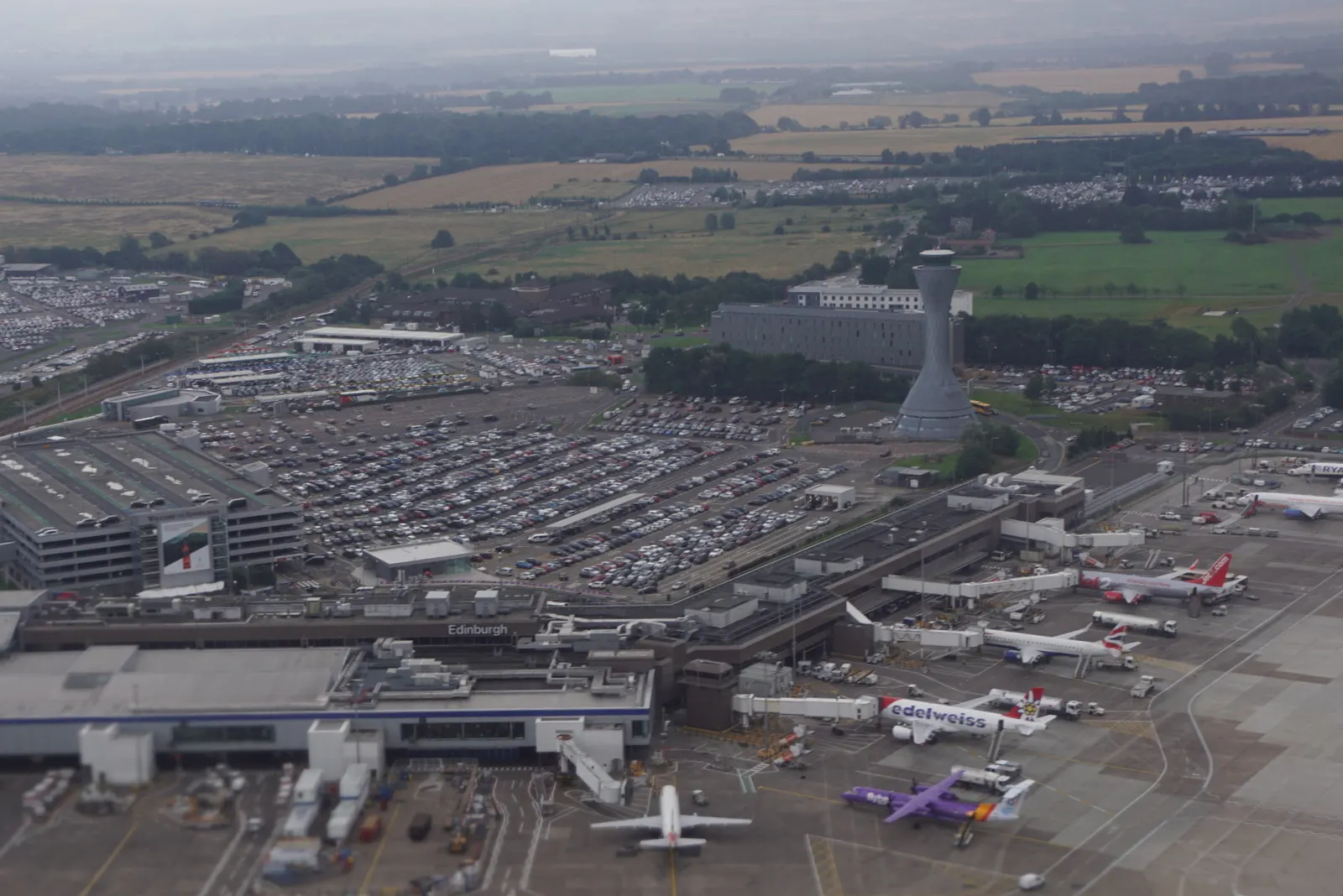 Aerial view of Edinburgh Airport showing the main terminal buildings, parallel runways, taxiways, and surrounding countryside.