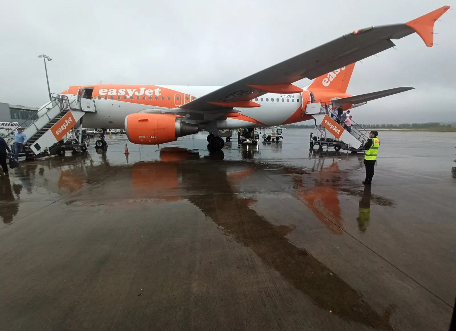 The airside departures area inside Edinburgh Airport with gate seating, flight information displays, and large windows overlooking parked aircraft.