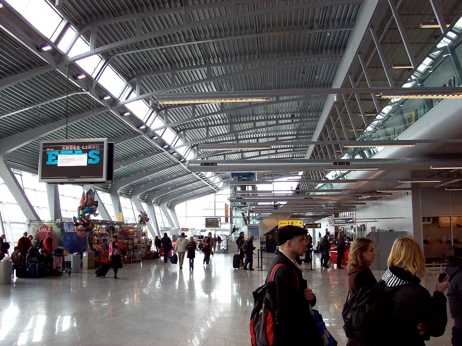 Landside view of the Eindhoven Airport terminal with parking and drop-off area in front.