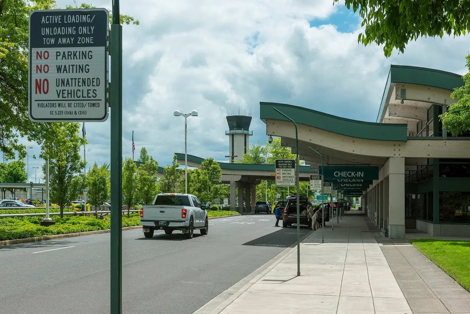 Check-in curb and civil air-traffic control tower at Eugene Airport in June 2022.