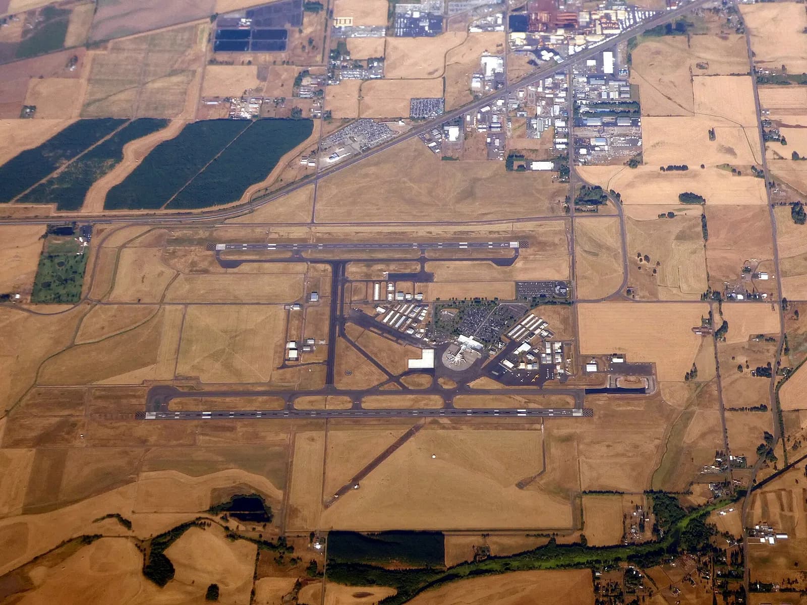 Aerial view of Eugene Airport showing both parallel runways and the civil terminal in July 2024.
