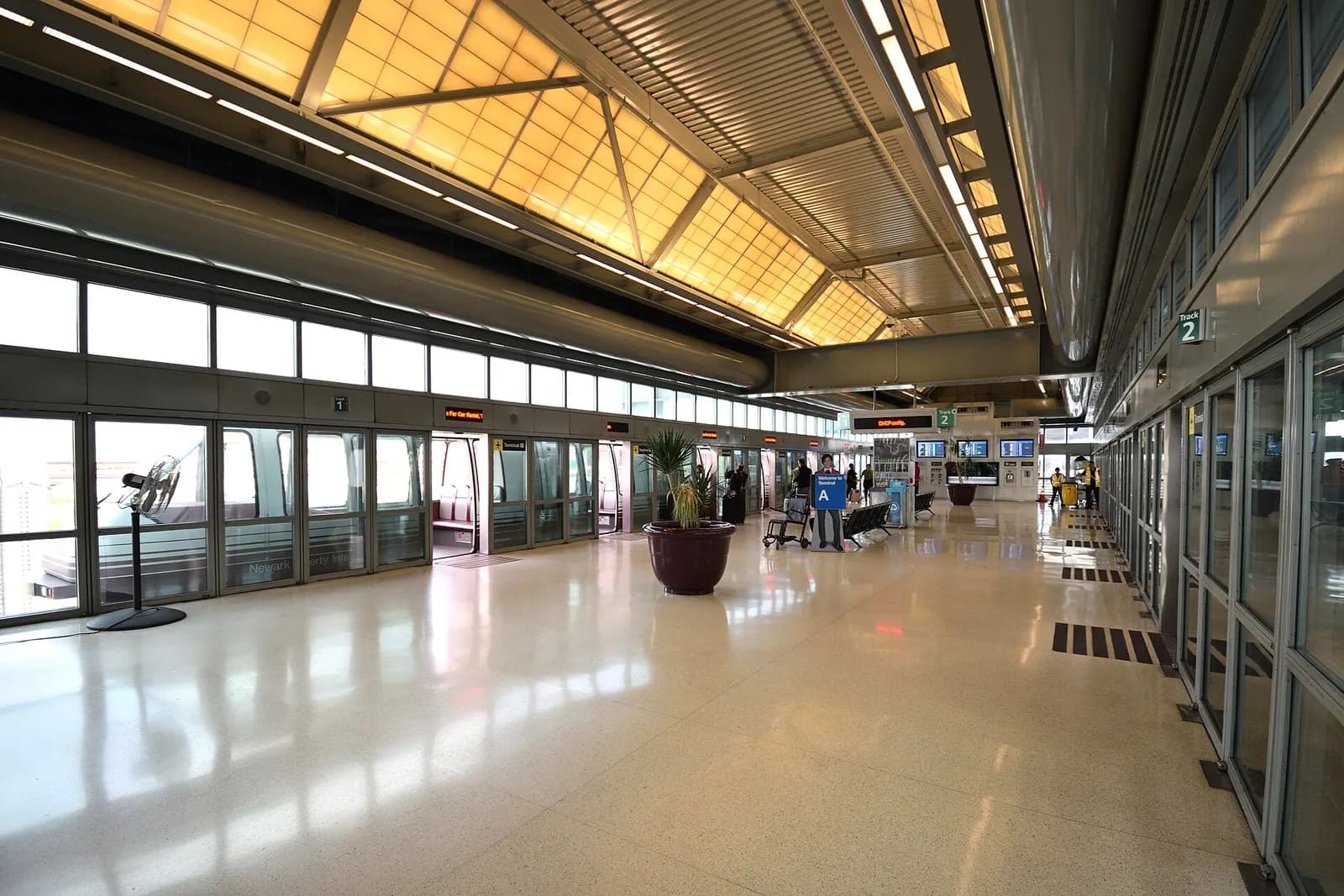 The interior of the Terminal A AirTrain station with platform edge, signage, and a view of the guideway.