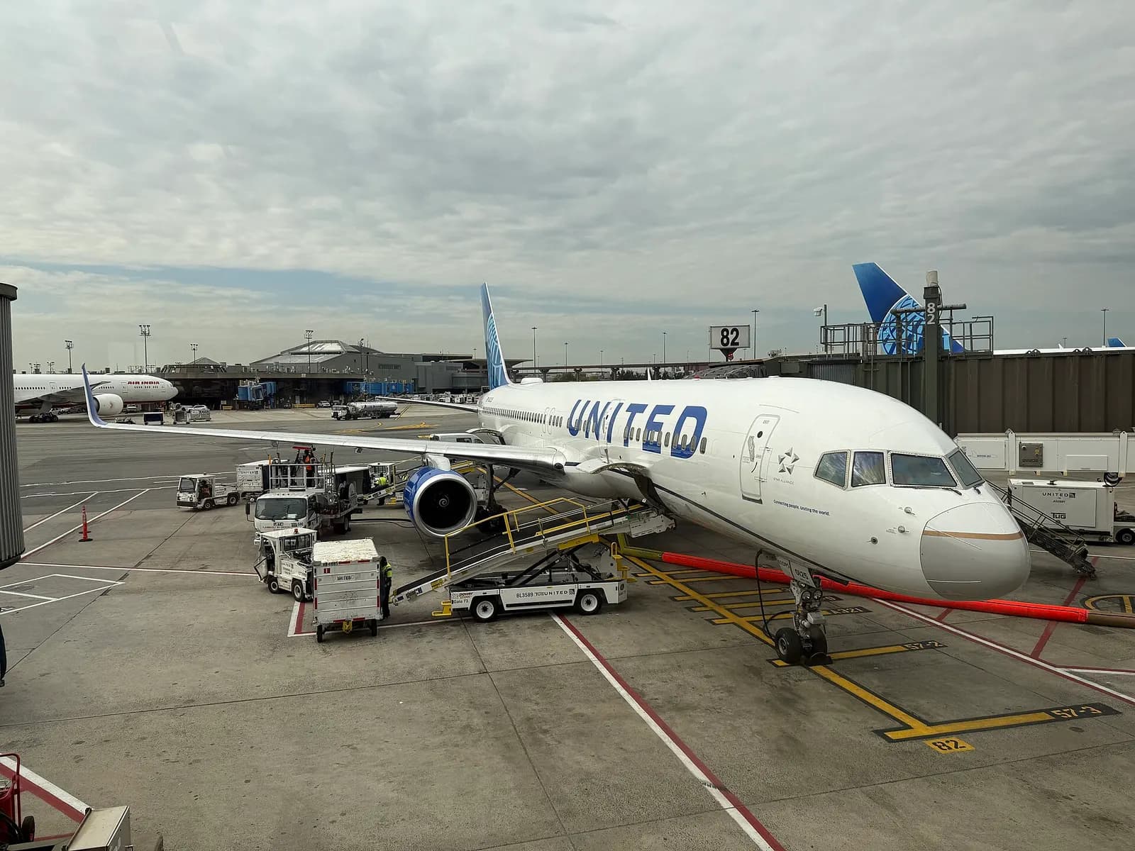 A United Airlines Boeing 757 parked at gate C82 with the jet bridge connected and the gate area visible.