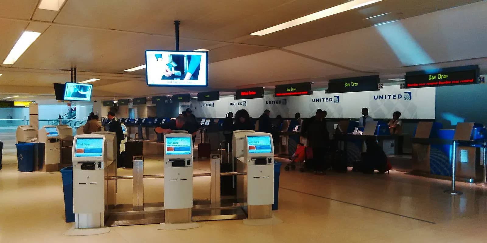 Travelers stand in line at airline check-in counters beneath Terminal B's arched ceiling.