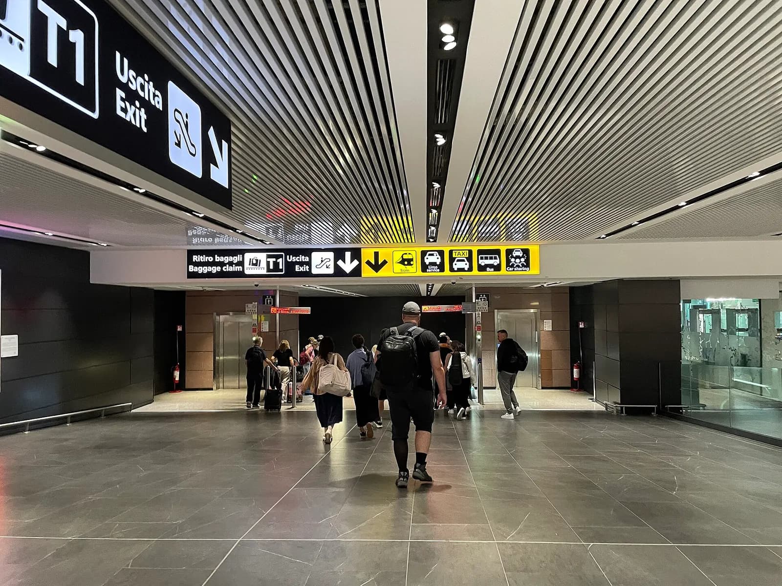 Terminal 1 arrivals hall with baggage claim carousels, signage, and passengers collecting luggage.
