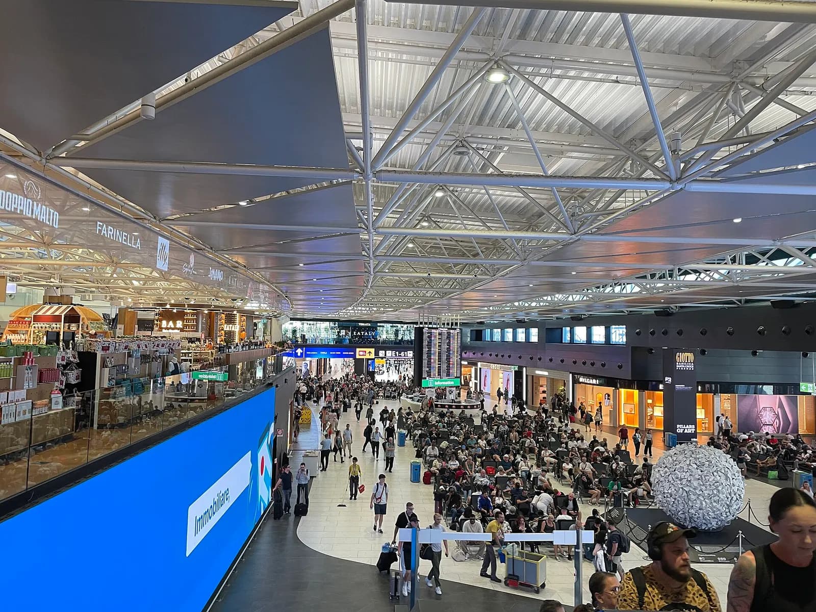 Spacious airside main hall inside Terminal 1 with high ceilings, bright lighting, and passenger walkways.