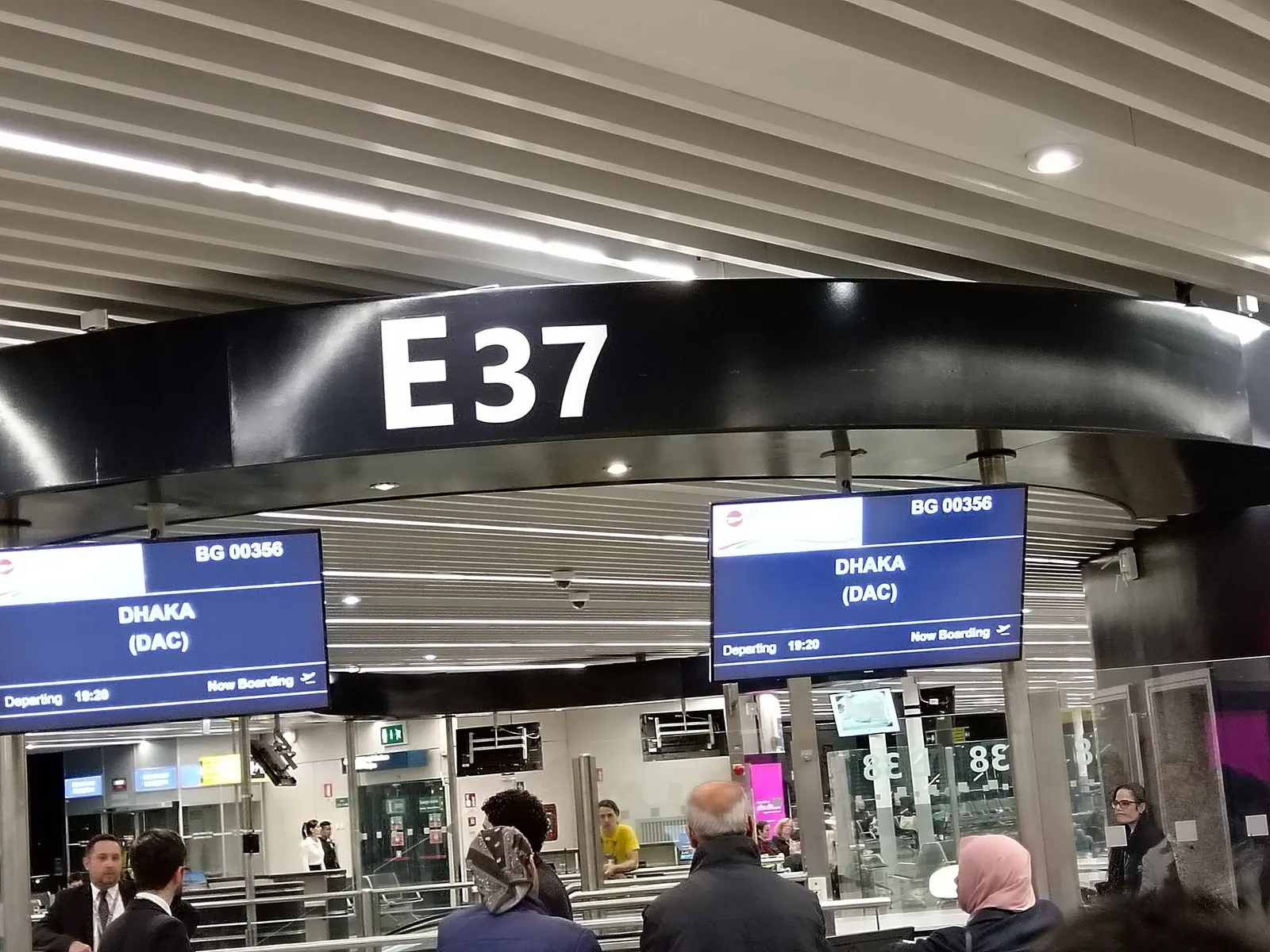 A departure gate area at FCO with seating, gate signage, and windows overlooking the tarmac.