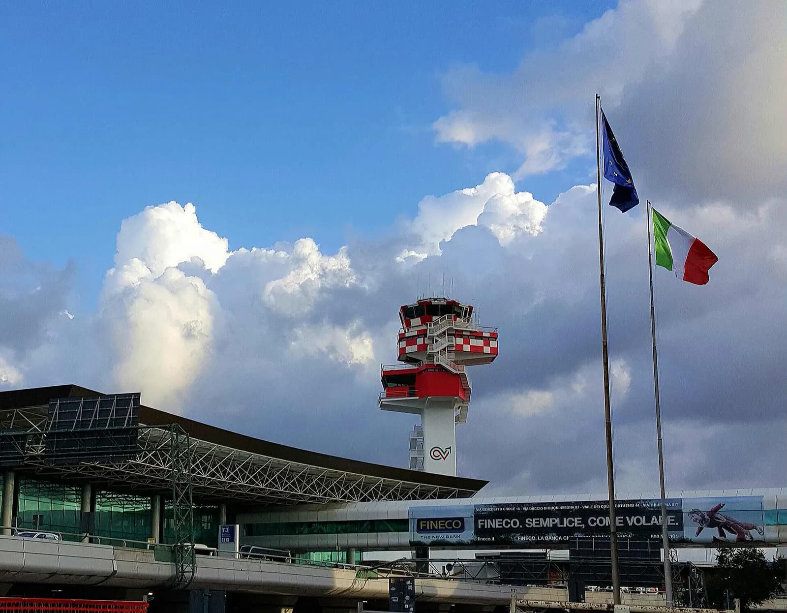 The renovated ENAV air traffic control tower standing beside Fiumicino Airport terminal structures.