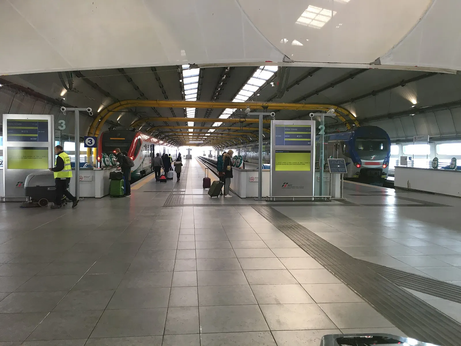 Fiumicino Aeroporto railway station platform with a Leonardo Express train on the left and a regional Rome–Fiumicino train on the right.