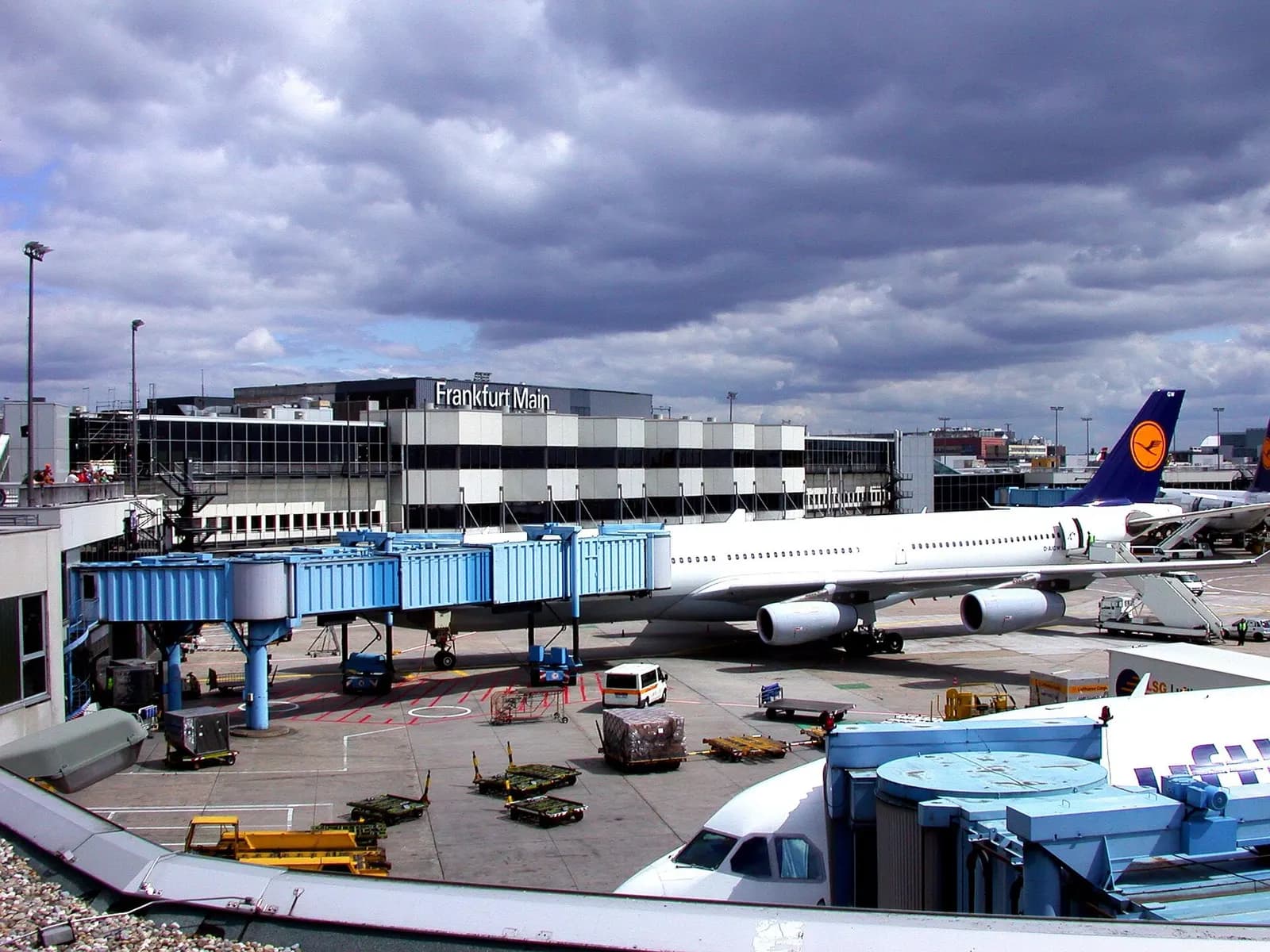A Lufthansa Airbus A340 connected to a jet bridge at Frankfurt Airport Terminal 1 with the terminal structure visible behind the aircraft.