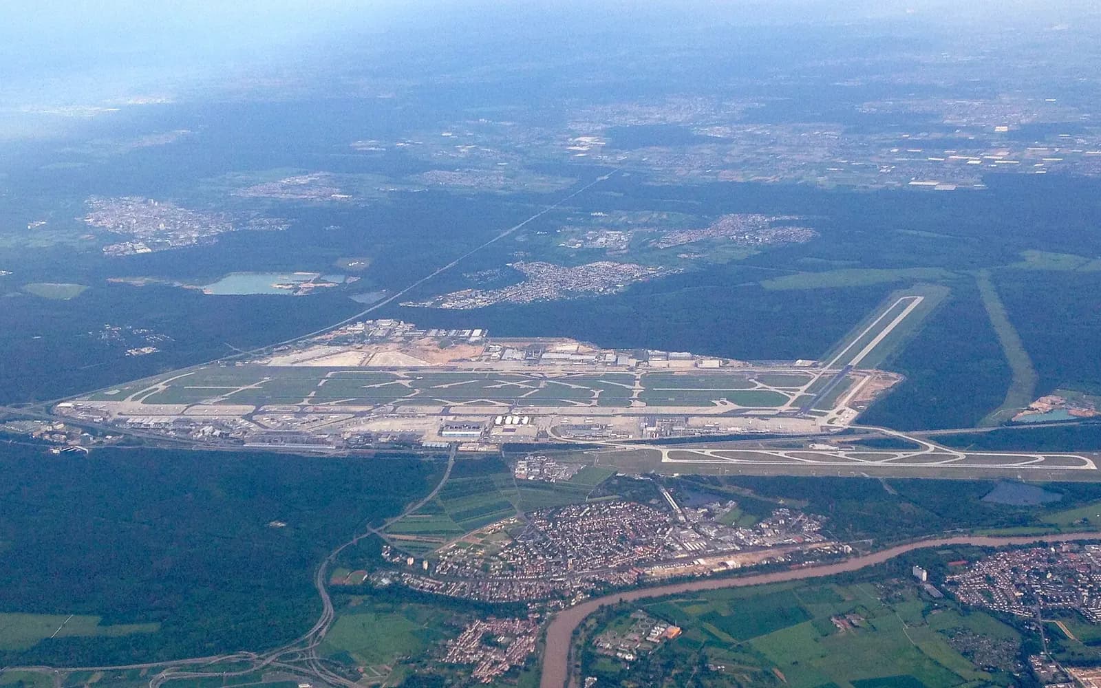 Aerial photograph of Frankfurt Rhein-Main Airport showing parallel runways, terminal buildings, cargo areas, and surrounding green countryside.