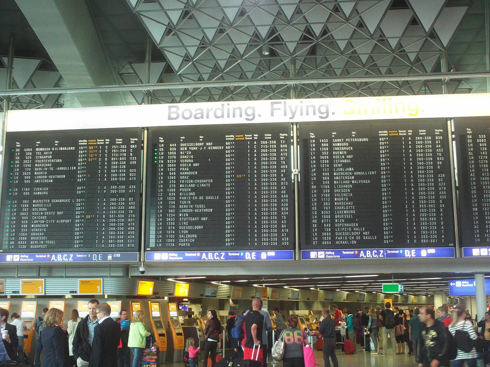 The Terminal 1 check-in area with rows of airline counters beneath large overhead flight departure information screens.
