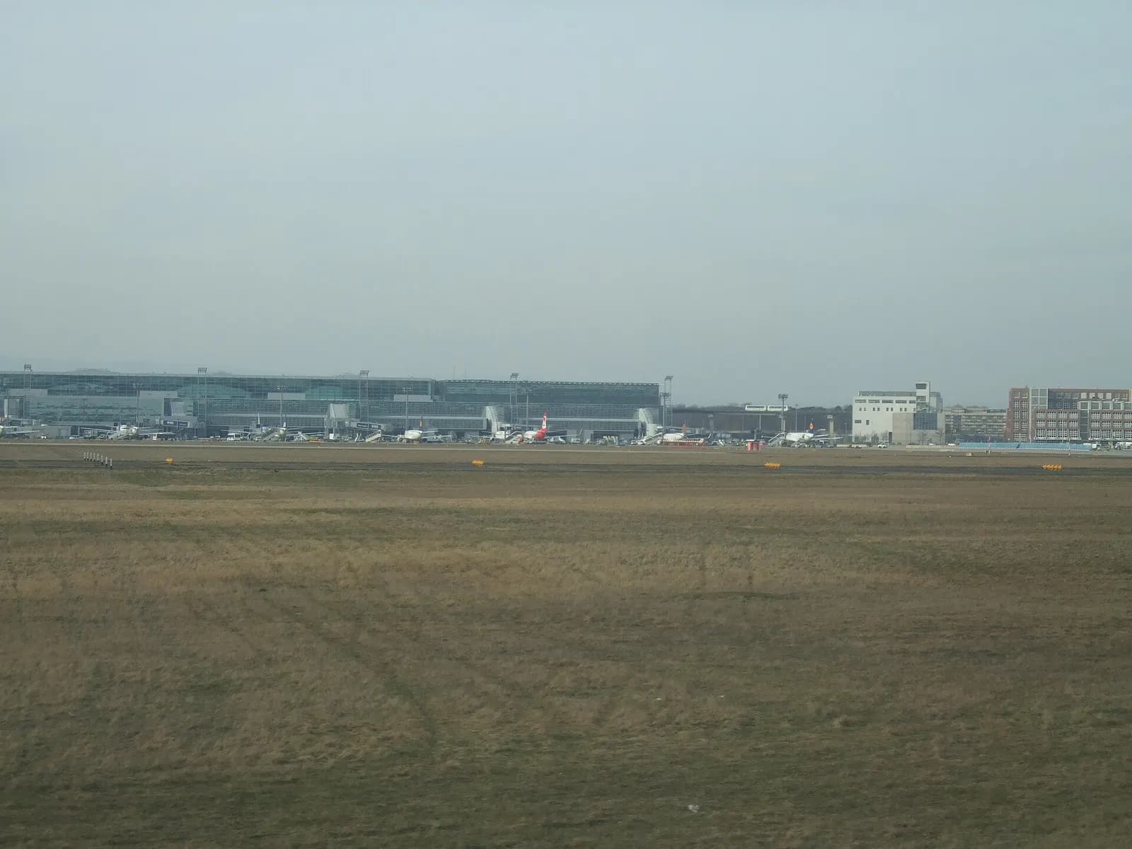 Exterior view of Frankfurt Airport Terminal 2 showing the terminal building, adjacent roadways, and aircraft at nearby gates.