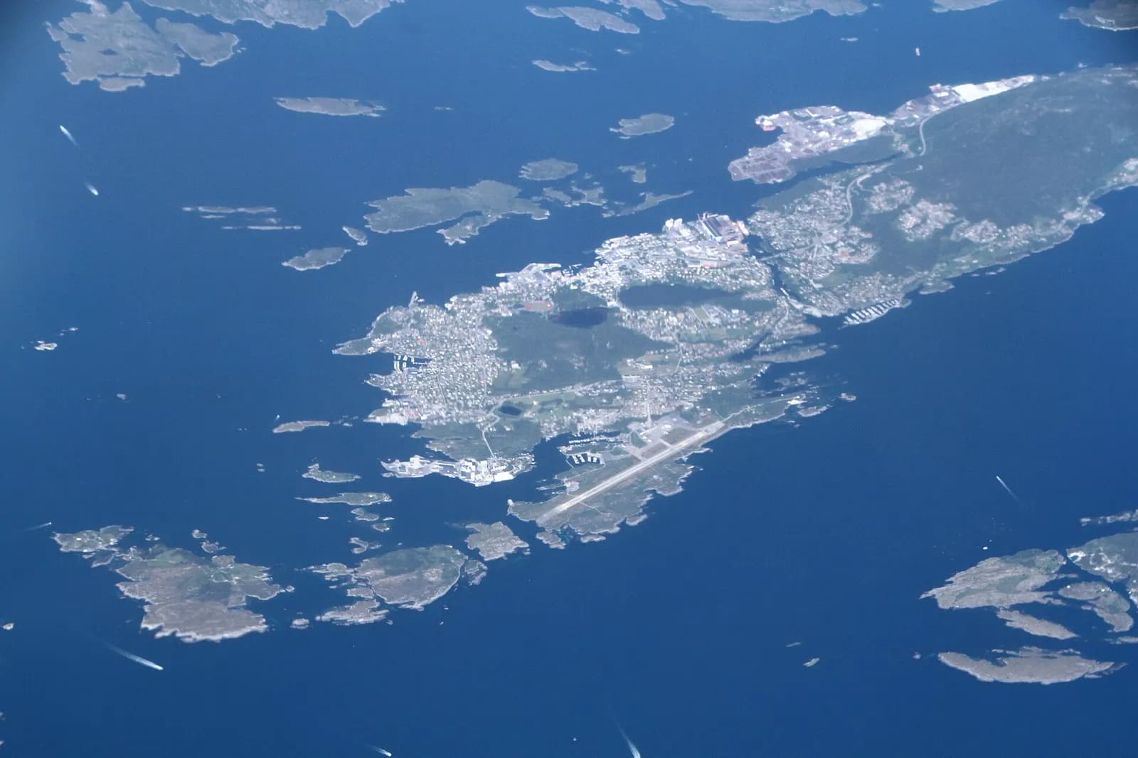 Southwest aerial over Florø’s coastal approaches with the airport strip in the landscape.