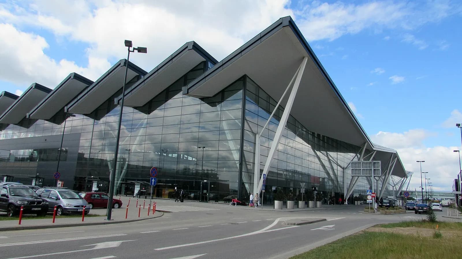 Exterior of Gdańsk Lech Wałęsa Airport showing terminal buildings, parking areas, and the airfield from ground level.
