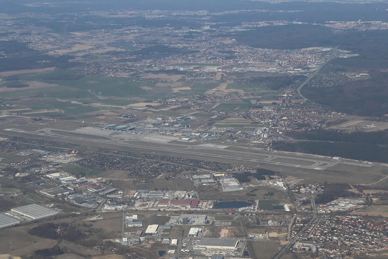 Aerial view of Gdańsk Lech Wałęsa Airport showing parallel runways, terminal buildings, aprons, and the surrounding fields and roads.