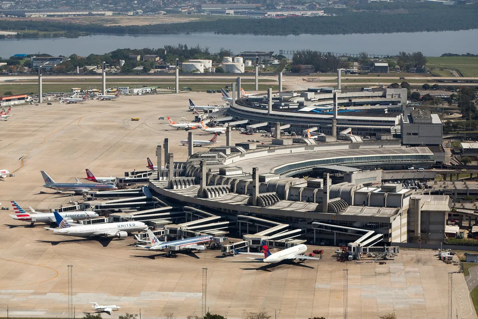 Aerial photograph of Galeão's passenger terminals, jet bridges, and aircraft lined up on surrounding taxiways and ramps.