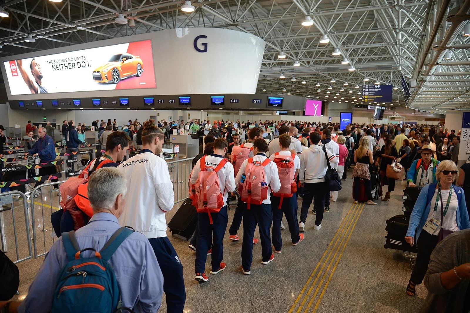 Crowded check-in and departures hall at Galeão filled with passengers, luggage, and airline counters during peak travel.