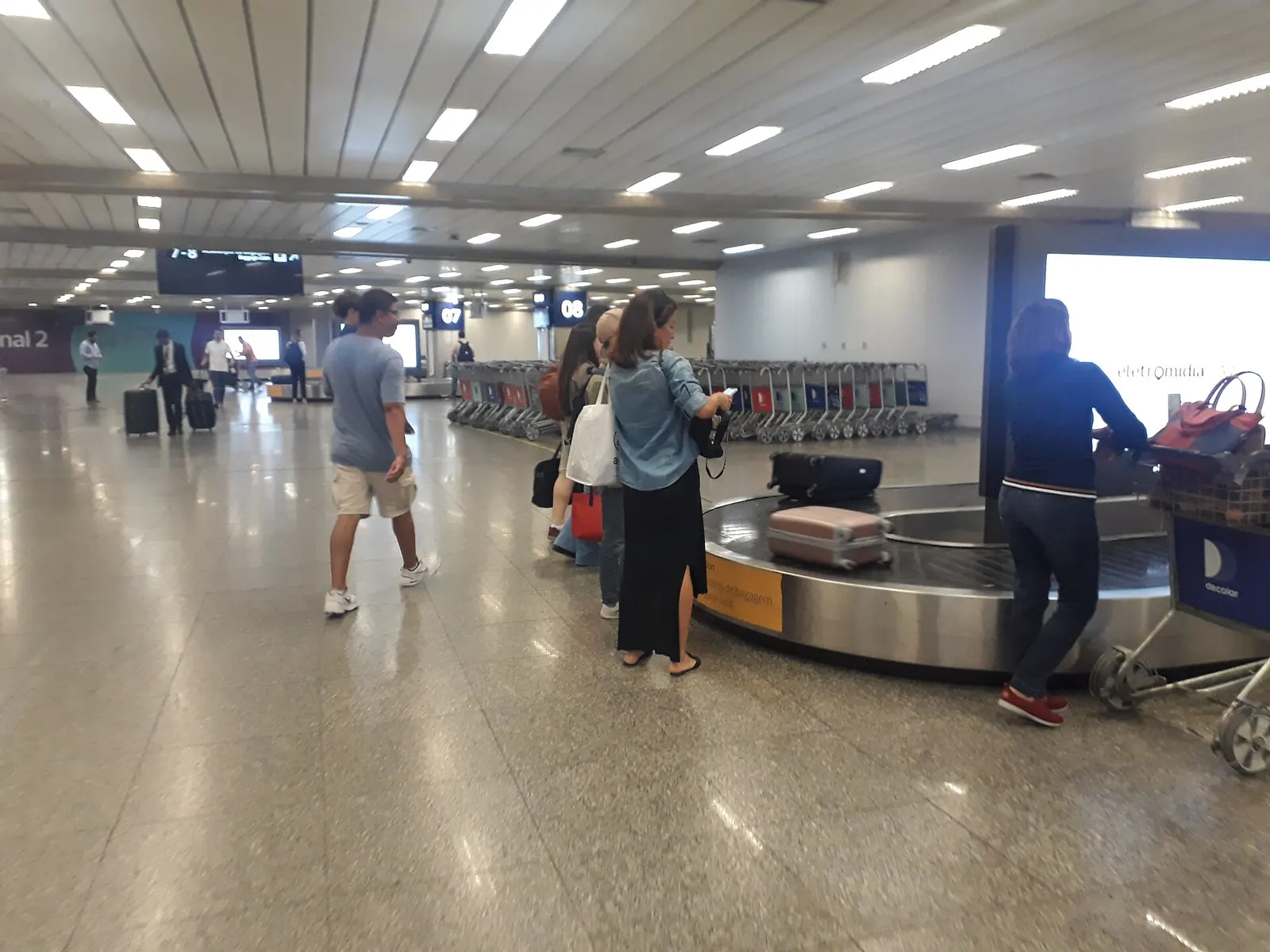 Domestic baggage claim hall in Terminal 2 with multiple carousels, monitors, and travelers collecting luggage.