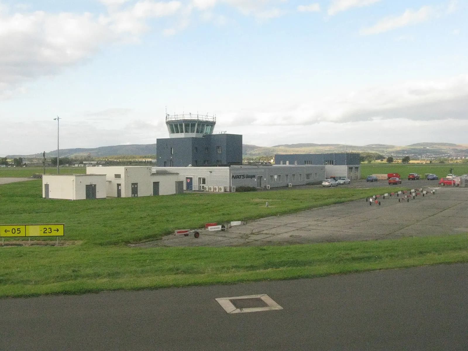 Glasgow Airport's air traffic control tower standing beside the terminal and airfield on a clear day.