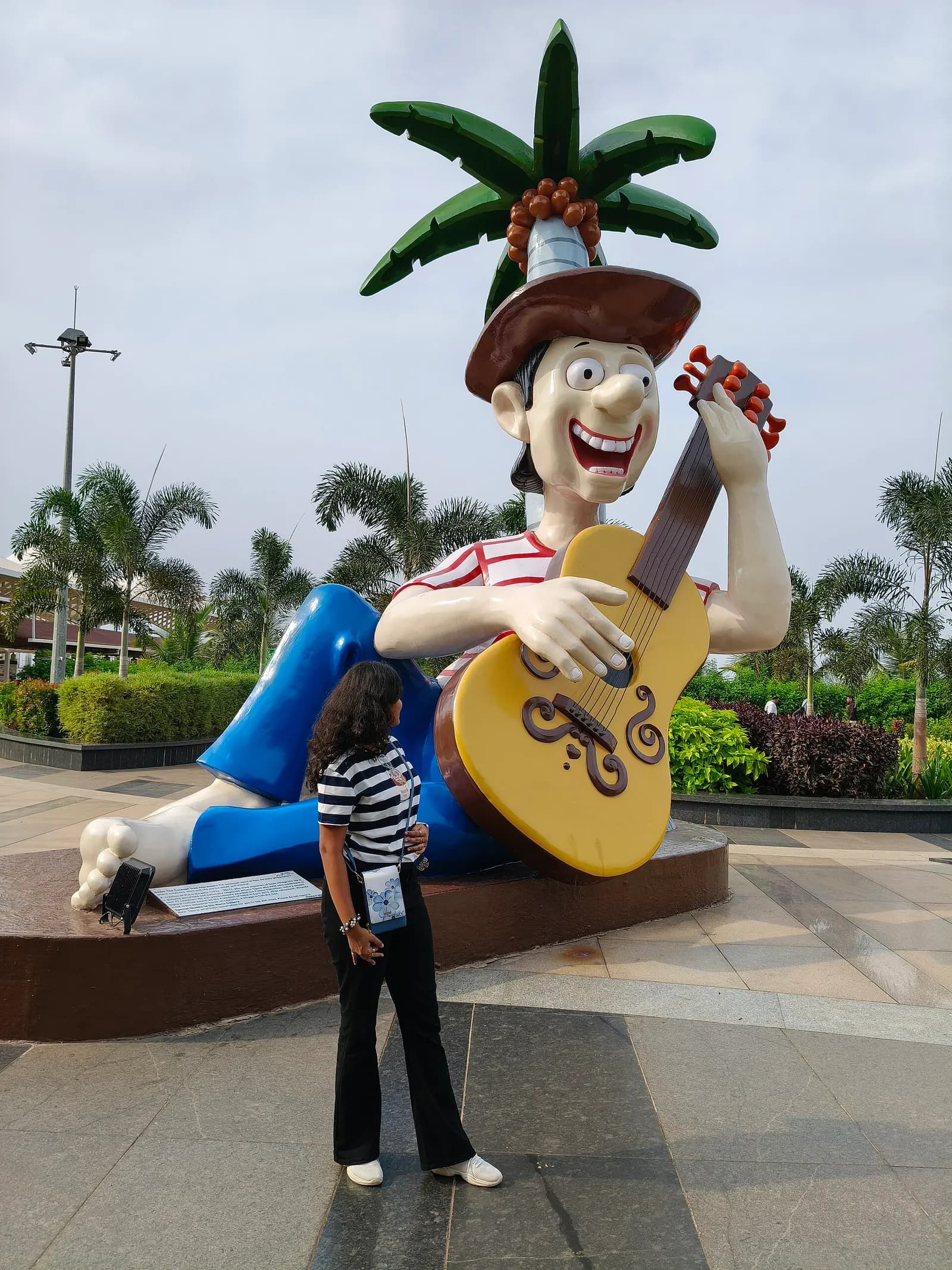 Mario Miranda–style guitarist sculpture on the landside plaza at Manohar International Airport (GOX)