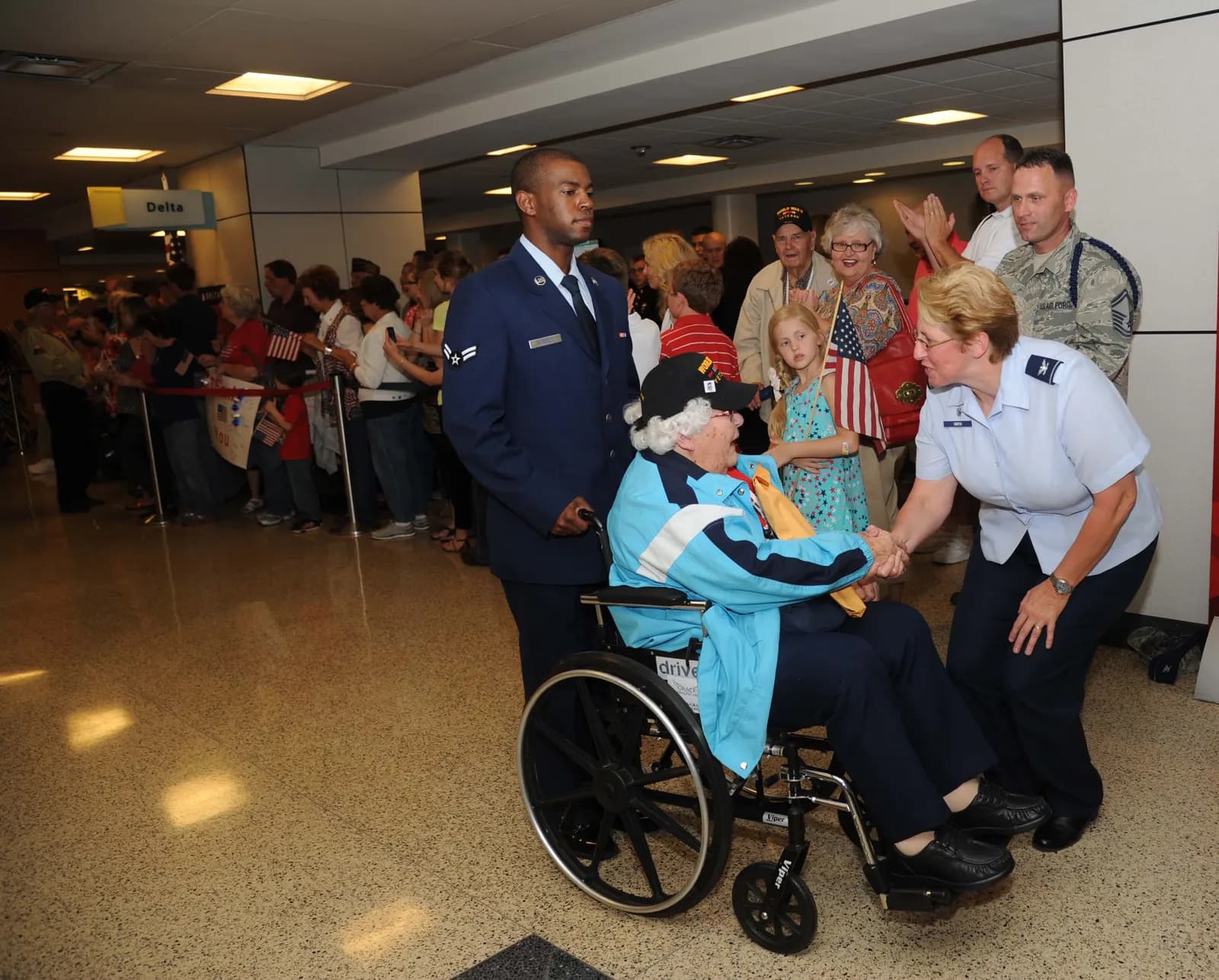 Honor-flight greeting in the Gulfport–Biloxi hall with a leftover Delta sign, 23 April 2013