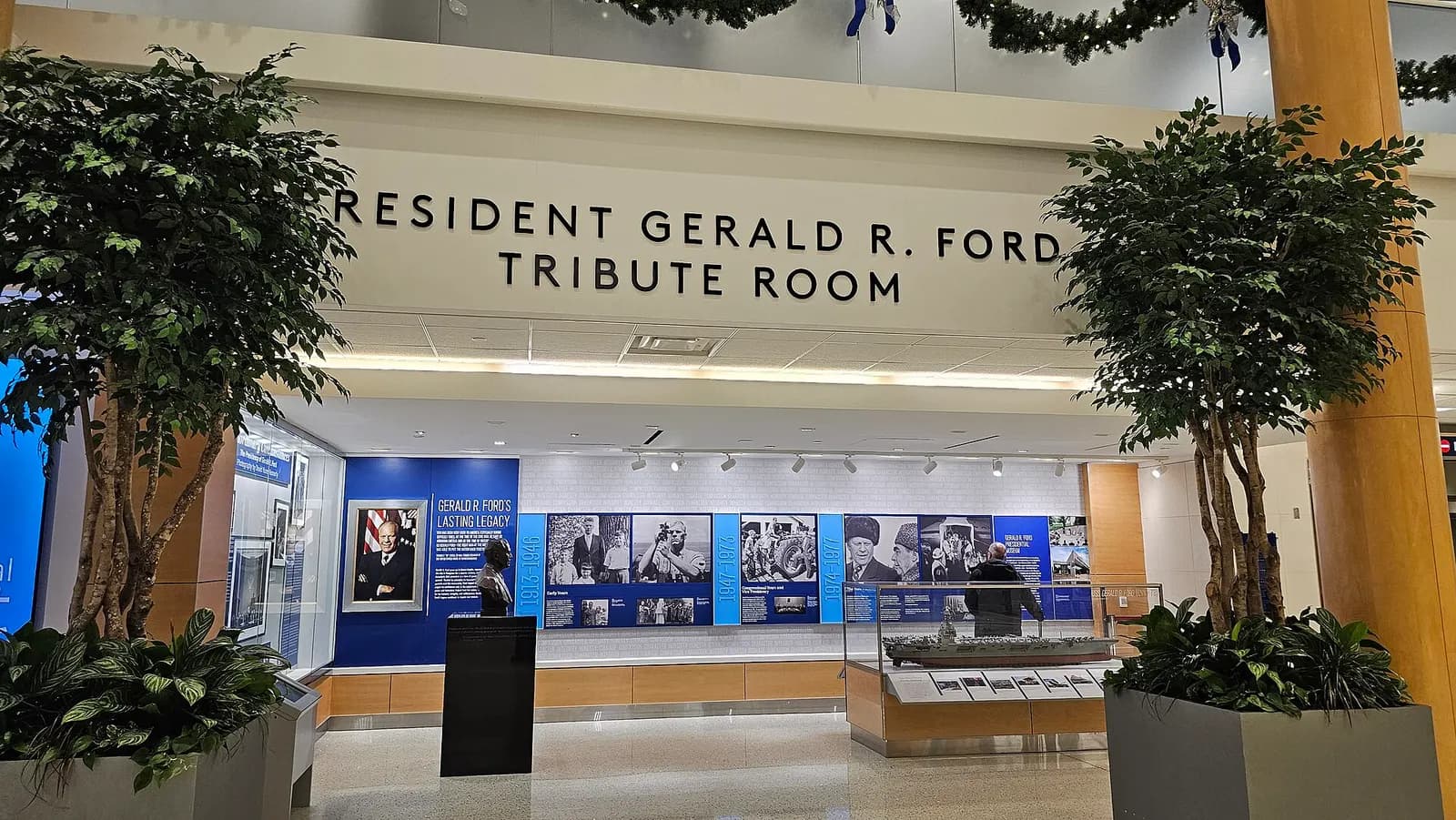 Landside President Gerald R. Ford Tribute Room at Gerald R. Ford International Airport, with display cases and Ford memorabilia under warm lighting.