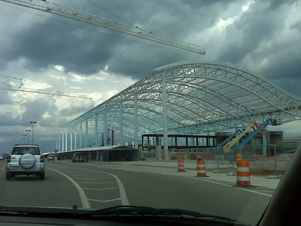 Construction fencing and earthwork at a Gerald R. Ford International Airport roadway entrance.