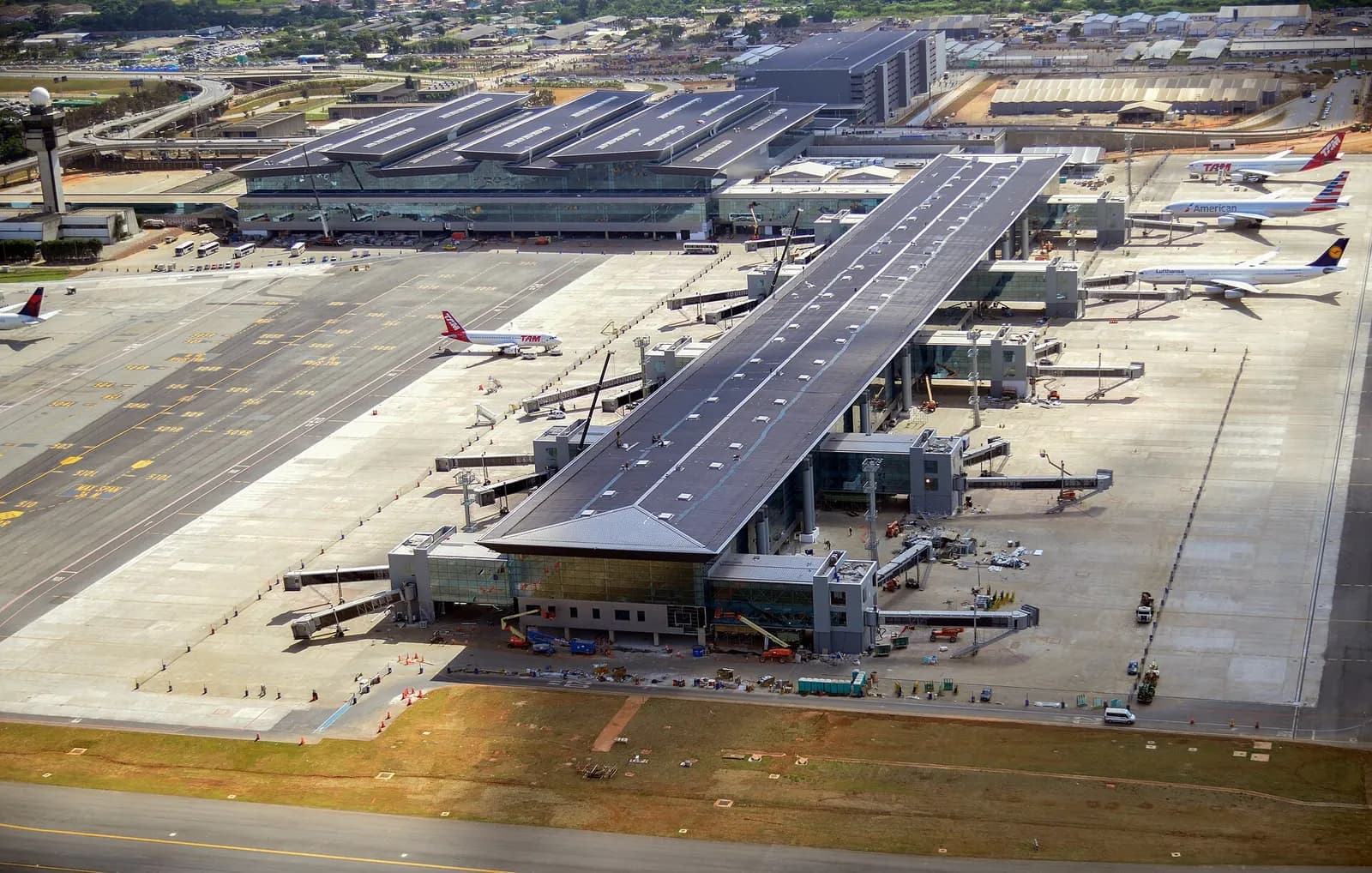 Exterior of the modern Terminal 3 at Guarulhos Airport with a curved glass-and-steel facade.