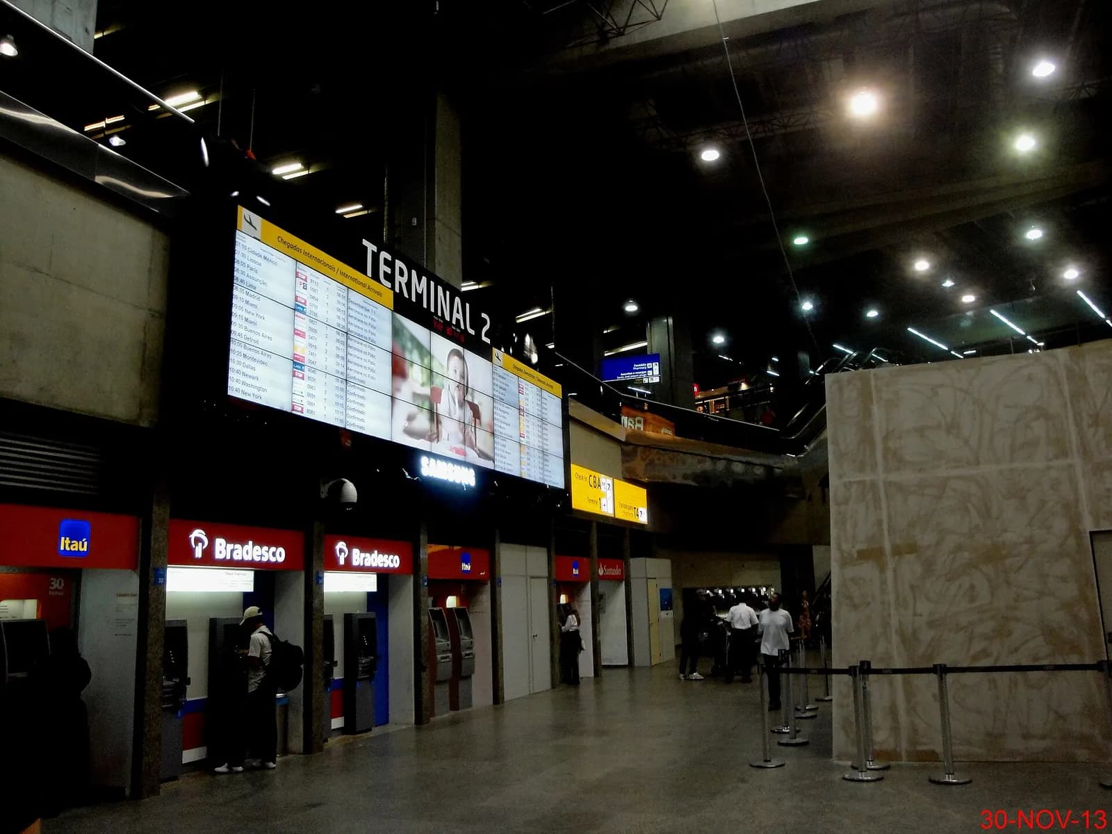 Bank ATMs and signage beside the free inter-terminal shuttle stop in Terminal 2 at GRU.
