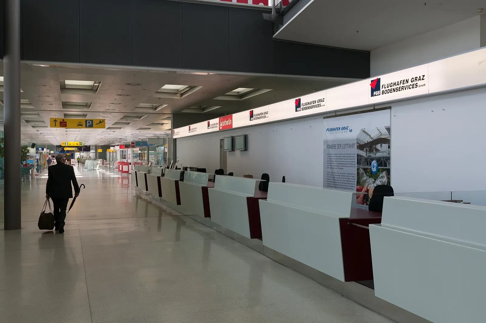 Empty check-in hall with Flughafen Graz Bodenservices counters and skylights